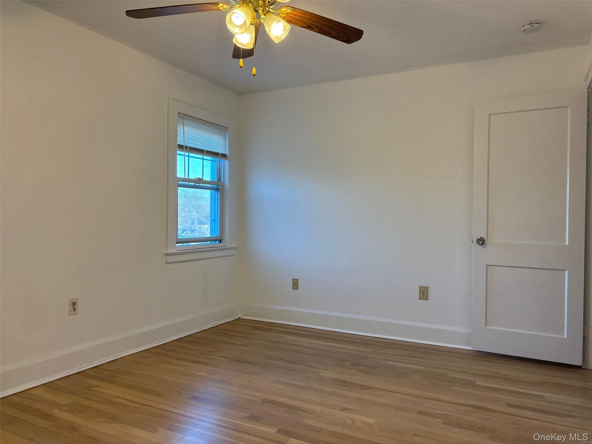 This room features hardwood floors, a window with blinds, and a ceiling fan with light fixture This room features hardwood floors, a window with blinds, and a ceiling fan with light fixture