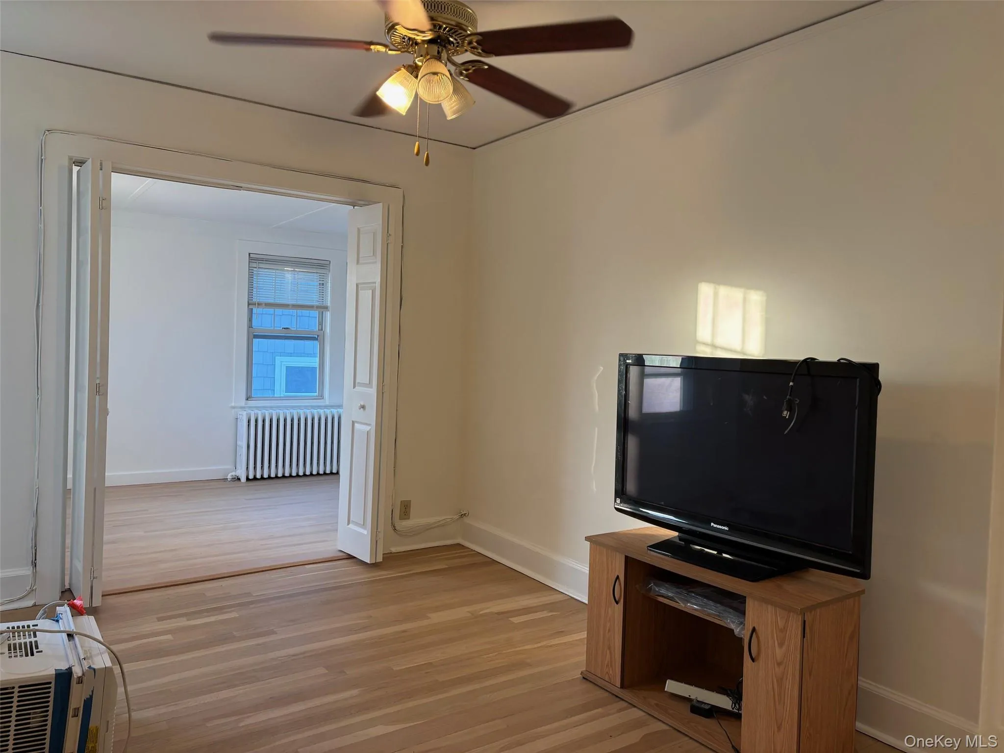 The room features hardwood flooring and a ceiling fan with integrated lighting The room features hardwood flooring and a ceiling fan with integrated lighting