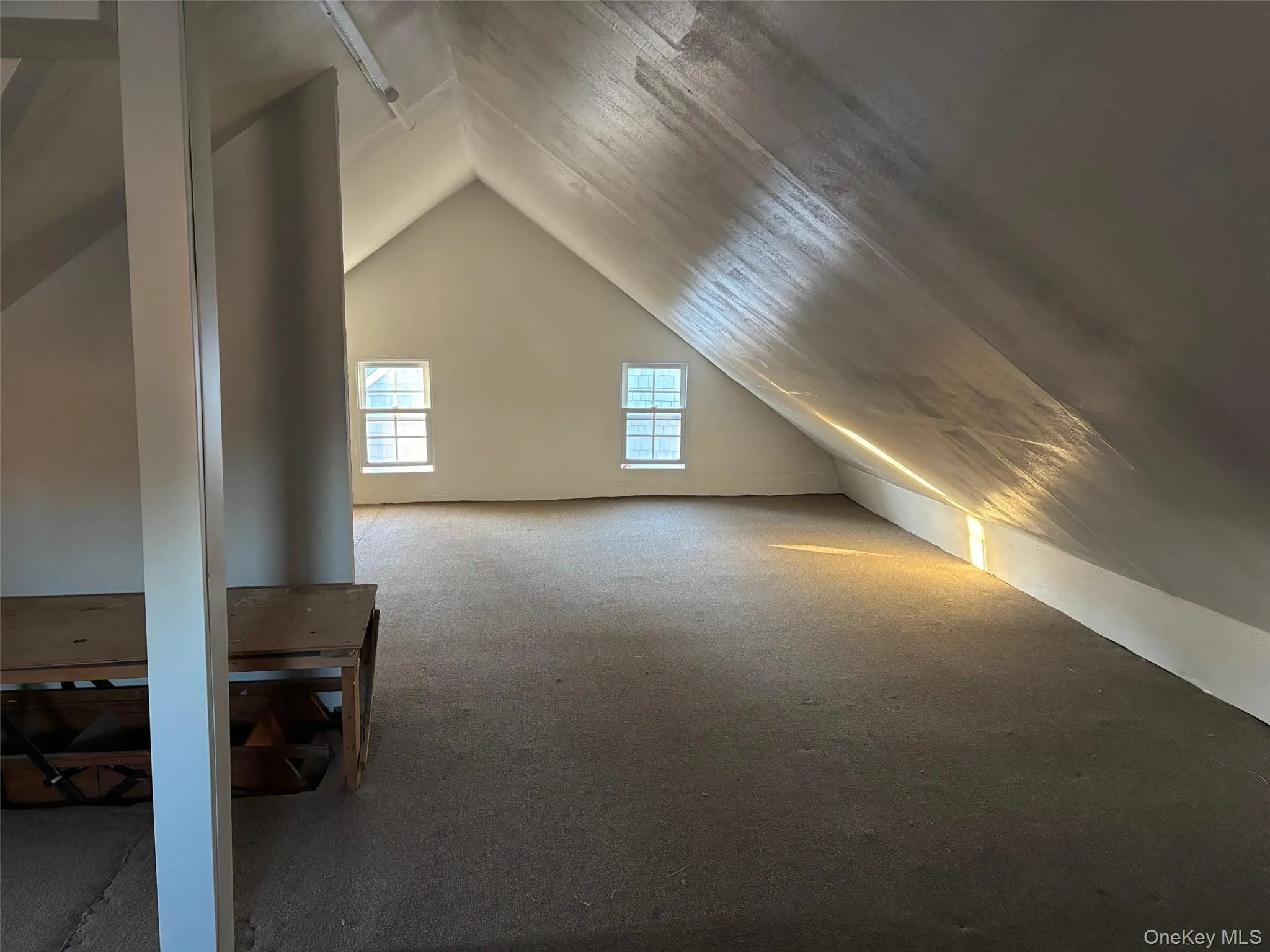 This expansive attic space features sloped ceilings, two windows providing natural light, and carpeting throughout This expansive attic space features sloped ceilings, two windows providing natural light, and carpeting throughout