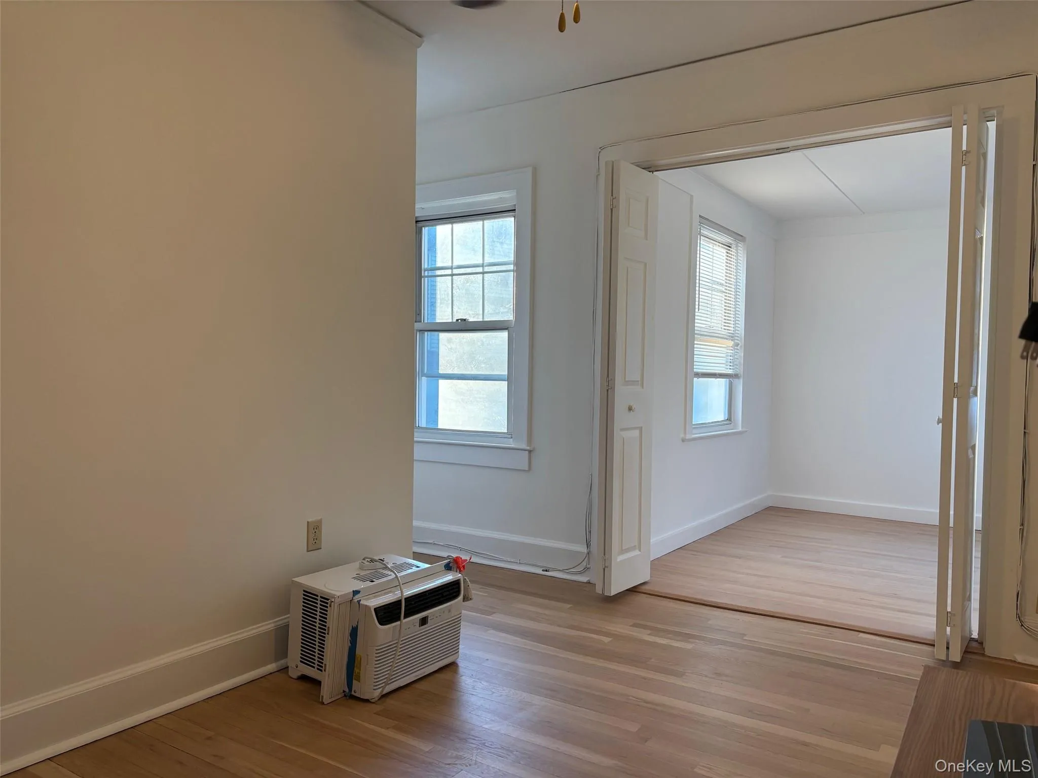 This interior space features light-colored hardwood flooring, white walls, and a window with multiple panes This interior space features light-colored hardwood flooring, white walls, and a window with multiple panes