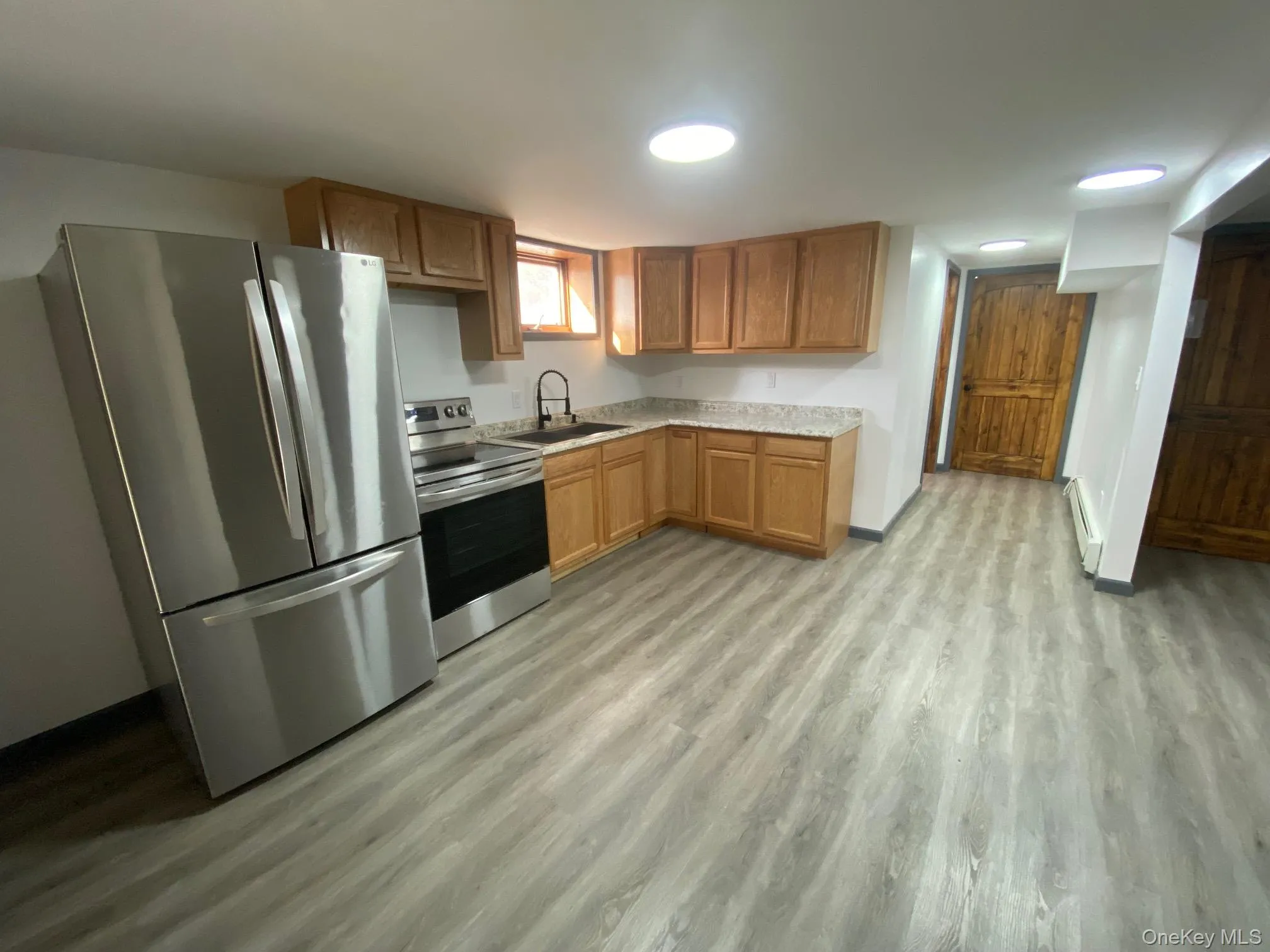 Kitchen with appliances with stainless steel finishes, light hardwood / wood-style flooring, baseboard heating, and sink Kitchen with appliances with stainless steel finishes, light hardwood / wood-style flooring, baseboard heating, and sink