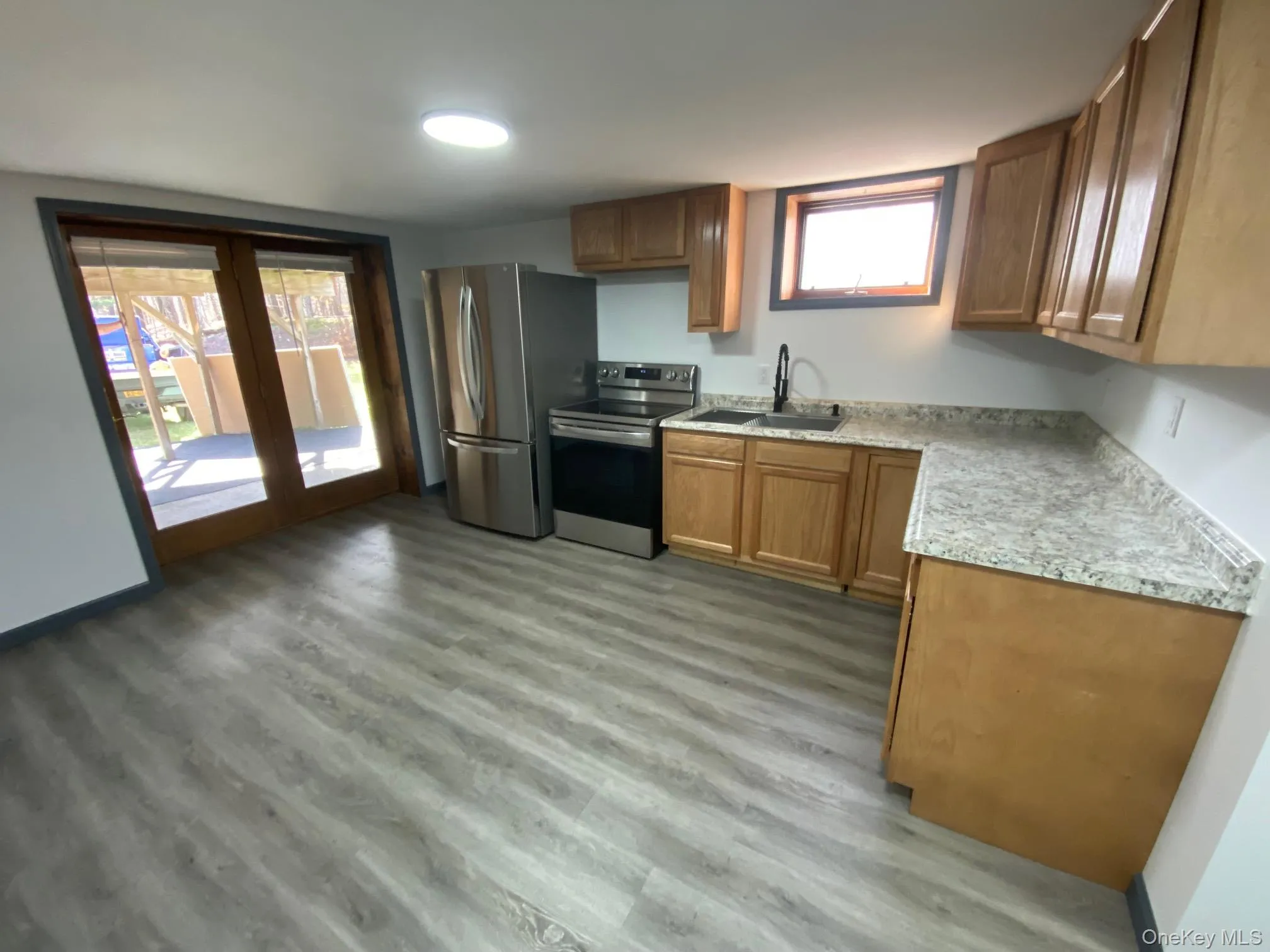 Kitchen with light wood-type flooring, sink, and appliances with stainless steel finishes Kitchen with light wood-type flooring, sink, and appliances with stainless steel finishes