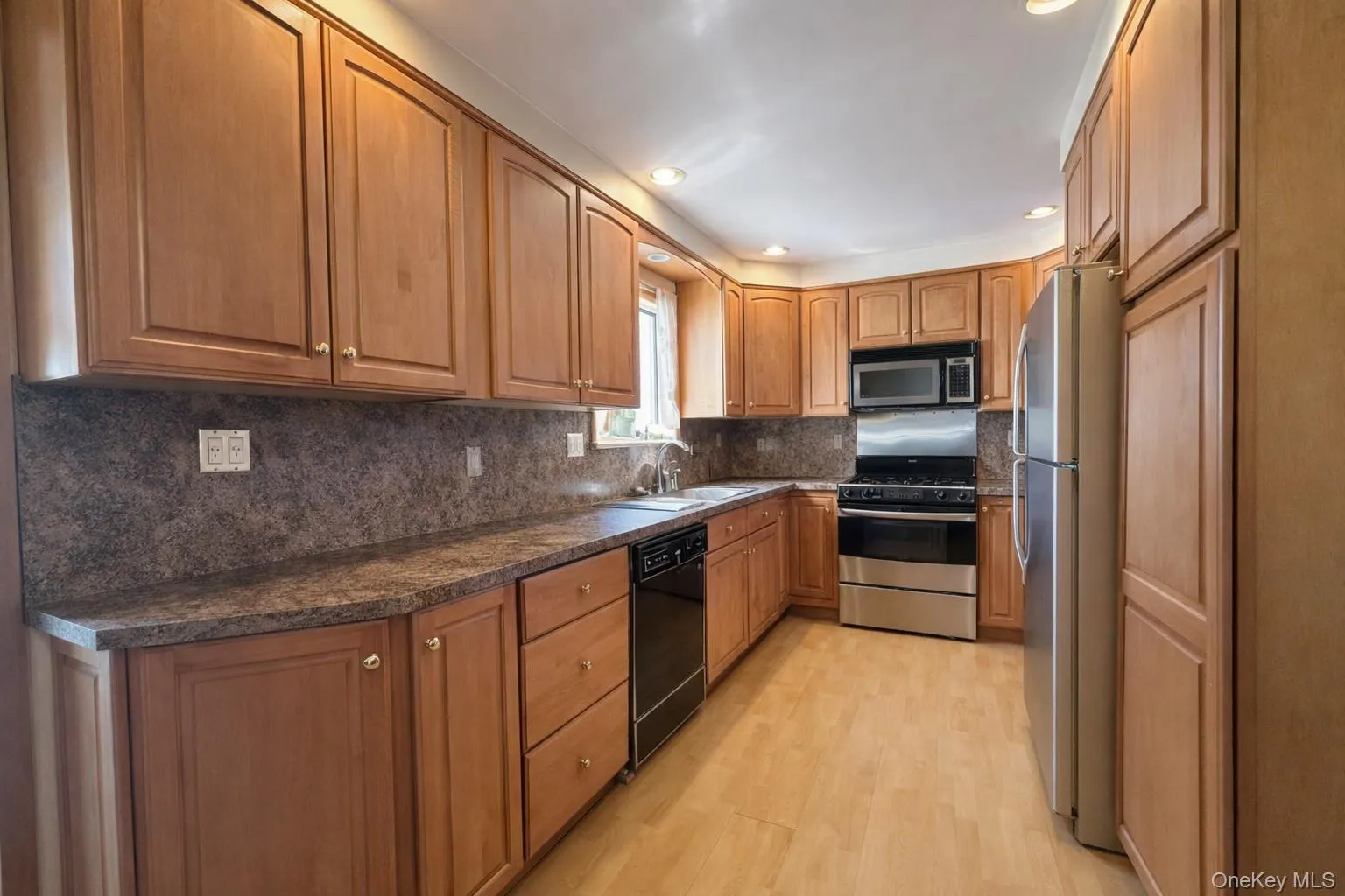 The property features a kitchen with light wood cabinetry, dark countertops, and stainless steel appliances including a refrigerator, oven, and microwave The property features a kitchen with light wood cabinetry, dark countertops, and stainless steel appliances including a refrigerator, oven, and microwave