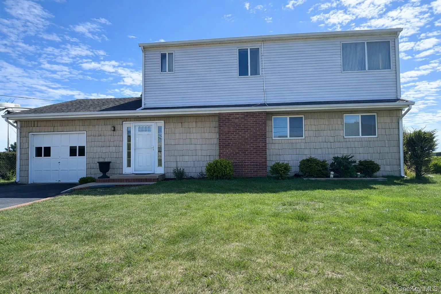 The property features a two-story exterior with a mix of siding and brick accents, a front lawn, and a paved driveway leading to an attached garage The property features a two-story exterior with a mix of siding and brick accents, a front lawn, and a paved driveway leading to an attached garage