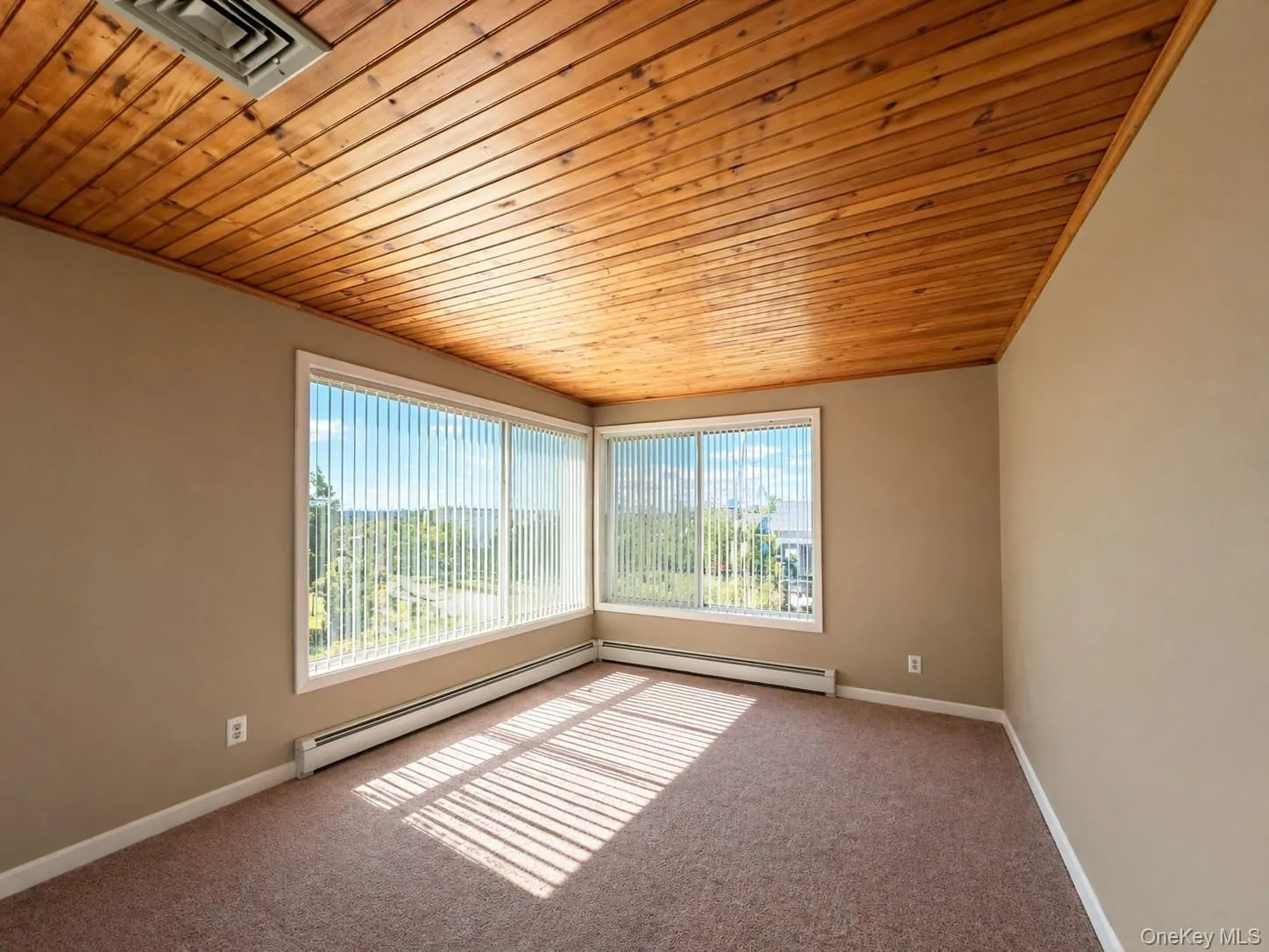 Room featuring a wood-panel ceiling and expansive windows with vertical blinds Room featuring a wood-panel ceiling and expansive windows with vertical blinds