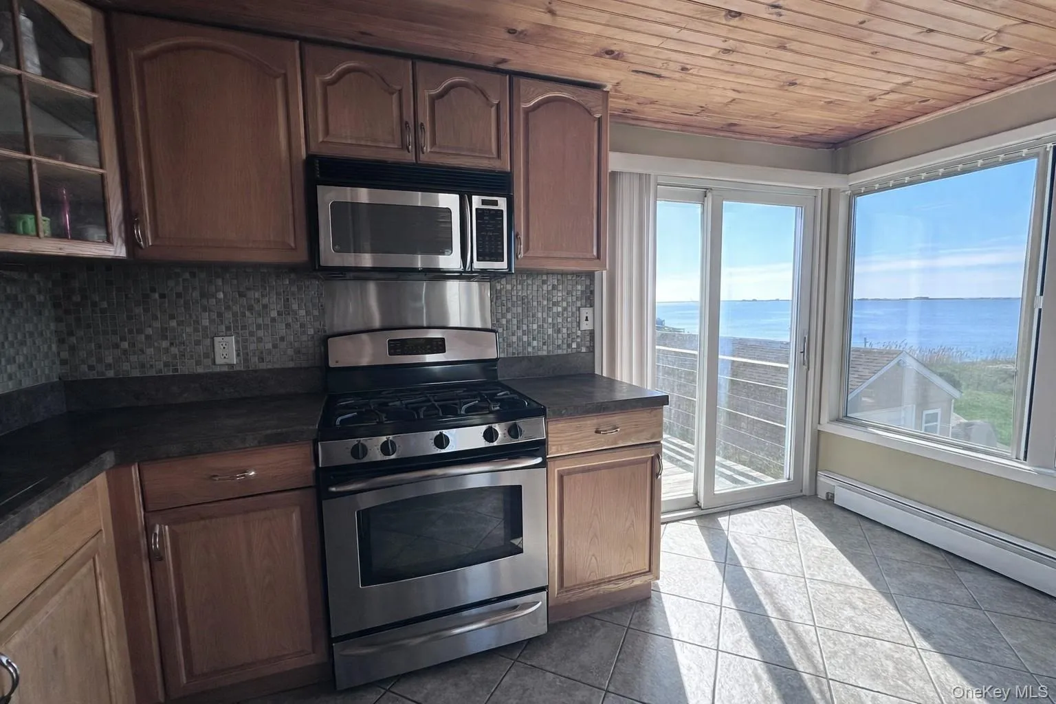 The kitchen features wooden cabinetry, stainless steel appliances, and a tiled backsplash The kitchen features wooden cabinetry, stainless steel appliances, and a tiled backsplash