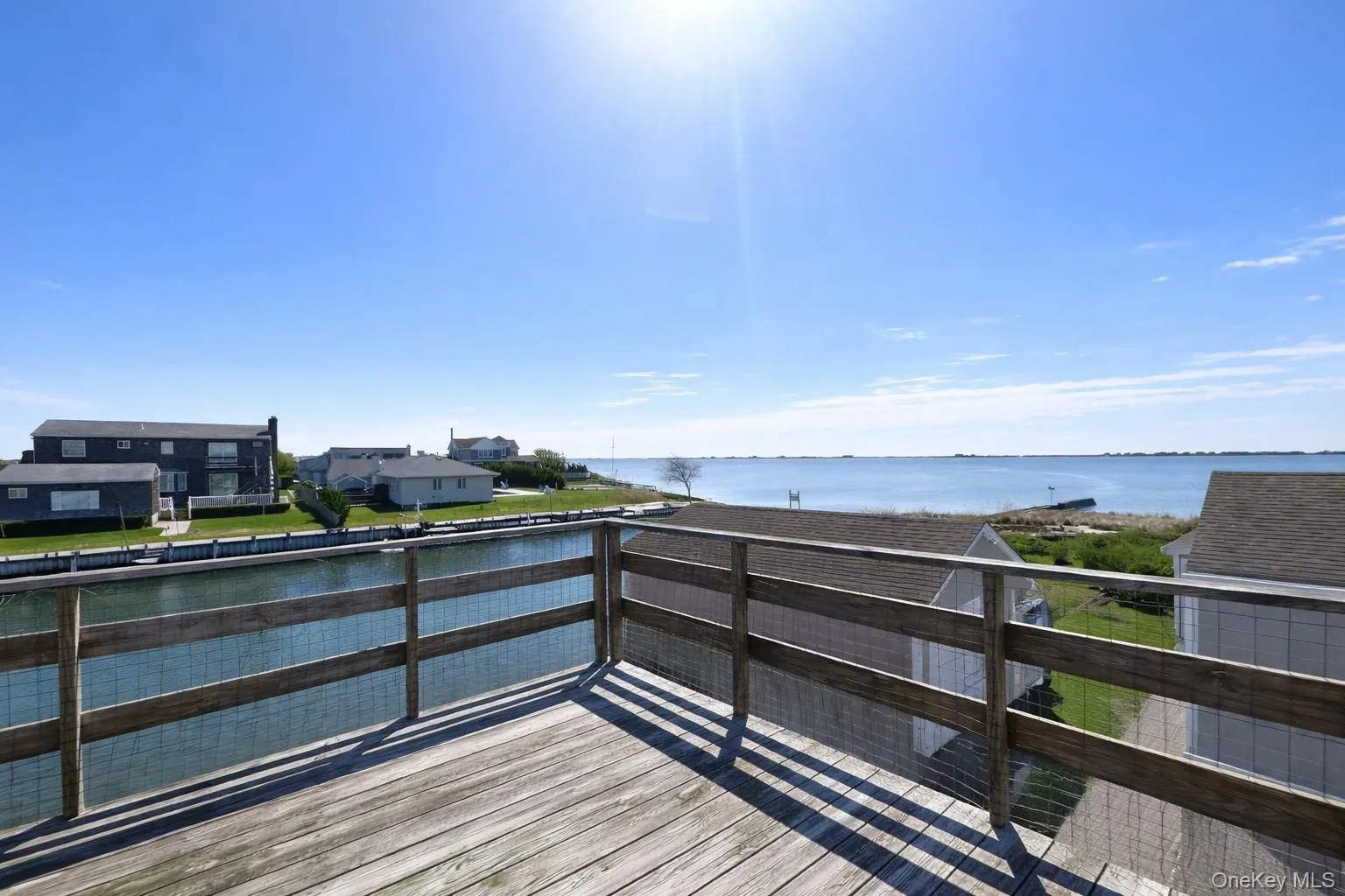Expansive outdoor deck with wooden railing overlooking a body of water, providing scenic water views Expansive outdoor deck with wooden railing overlooking a body of water, providing scenic water views
