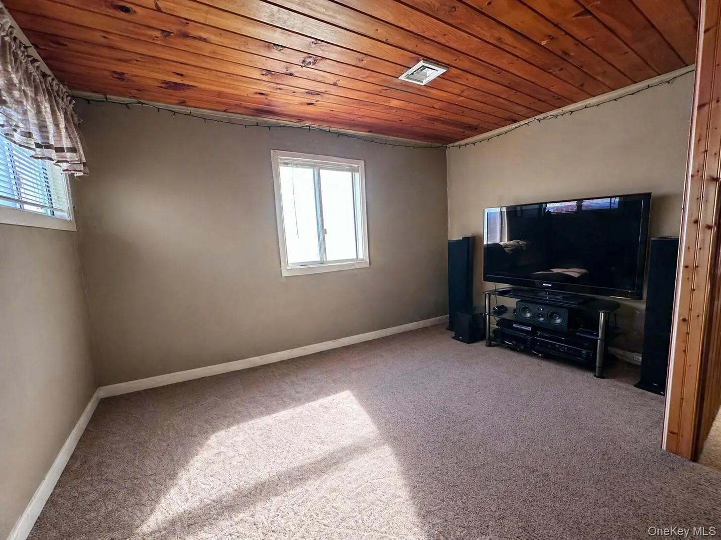 Room featuring a wood-finish plank ceiling, neutral wall paint, and two windows with blinds Room featuring a wood-finish plank ceiling, neutral wall paint, and two windows with blinds