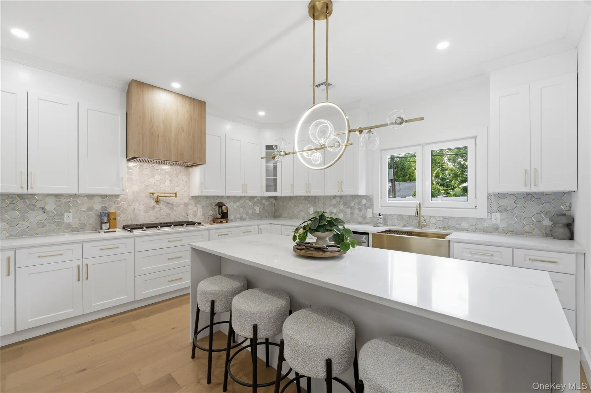 AMAZING Custom Chef's kitchen featuring white shaker cabinetry, light wood-finish flooring, a wood-paneled range hood, and a white countertop island AMAZING Custom Chef's kitchen featuring white shaker cabinetry, light wood-finish flooring, a wood-paneled range hood, and a white countertop island