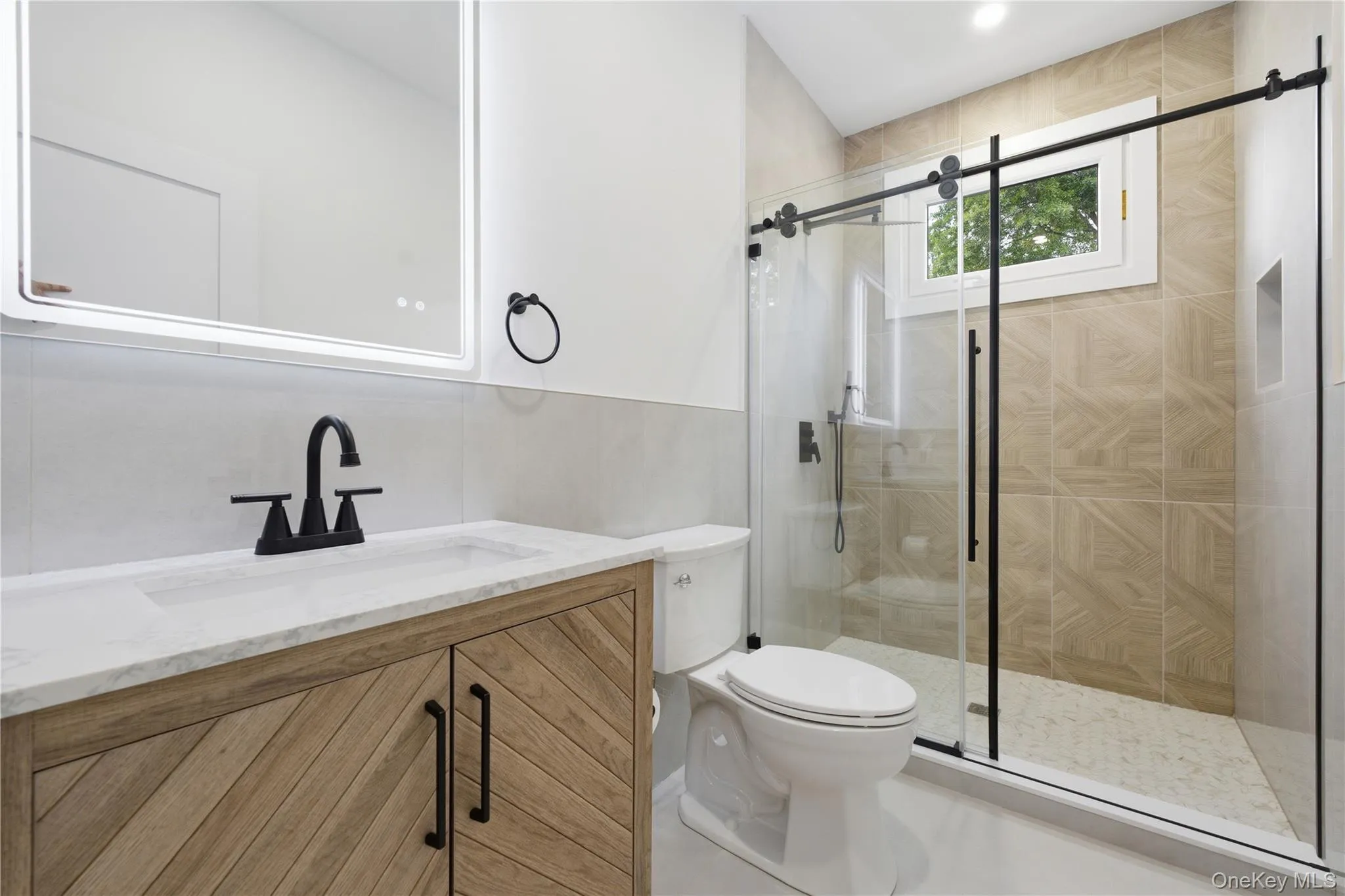 Bathroom featuring a wood-finish vanity with a white countertop and integrated sink, matte black faucet, and a lighted mirror. Custom gorgeous bathroom! Bathroom featuring a wood-finish vanity with a white countertop and integrated sink, matte black faucet, and a lighted mirror. Custom gorgeous bathroom!