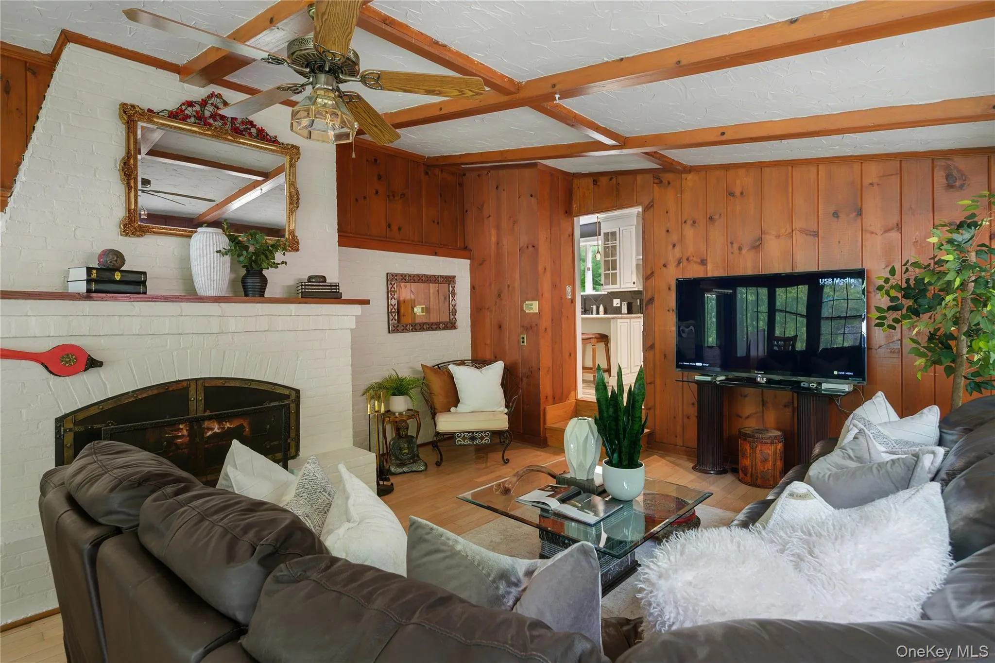 Family room with tongue and groove cedar paneling, fireplace with wrought iron details and brick surround, beamed ceiling, blood oak floors, door to back patio Family room with tongue and groove cedar paneling, fireplace with wrought iron details and brick surround, beamed ceiling, blood oak floors, door to back patio