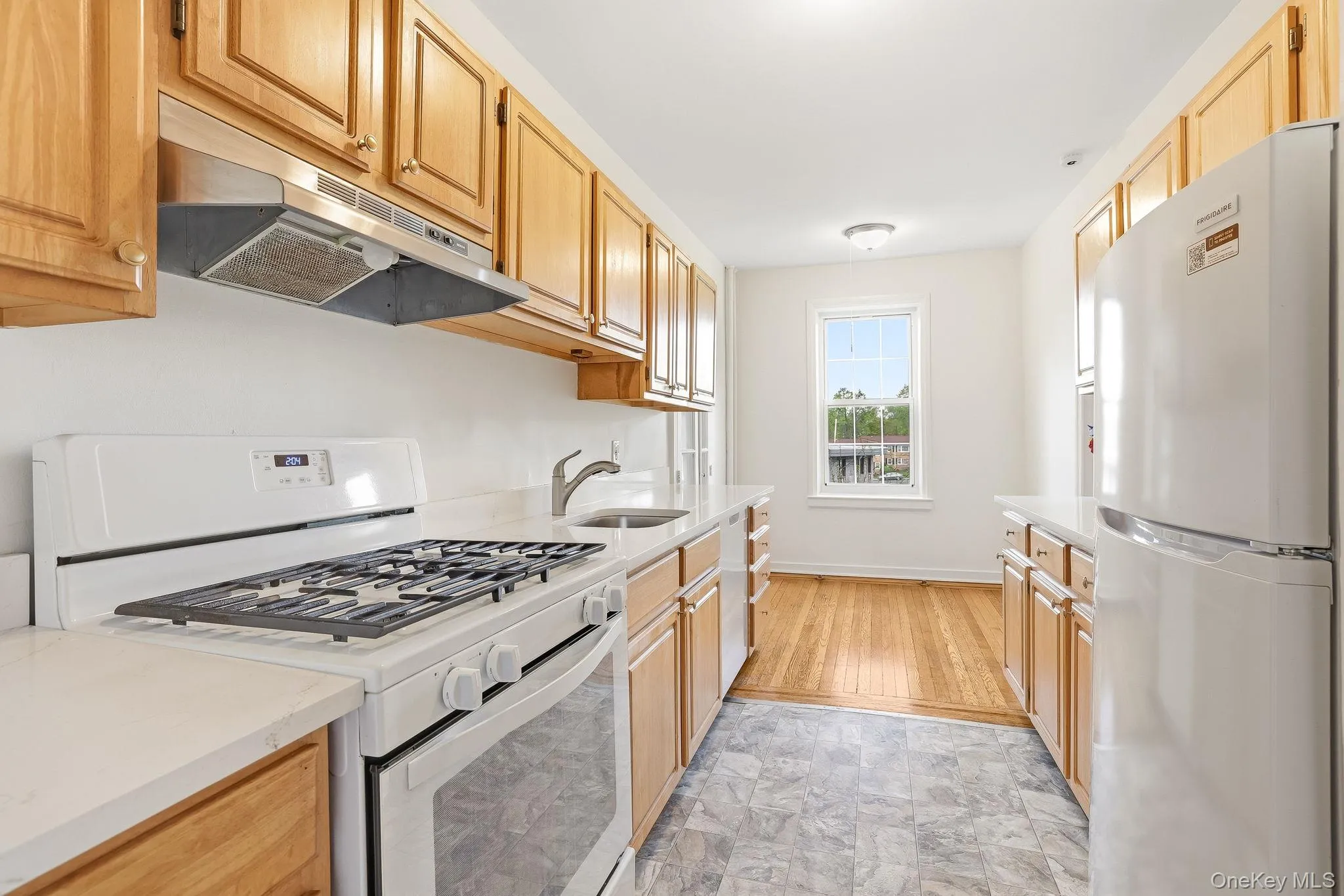 The kitchen with wood cabinetry has new french gold knobs and includes a gas-cooking range and exhaust hood, and free-standing microwave The kitchen with wood cabinetry has new french gold knobs and includes a gas-cooking range and exhaust hood, and free-standing microwave