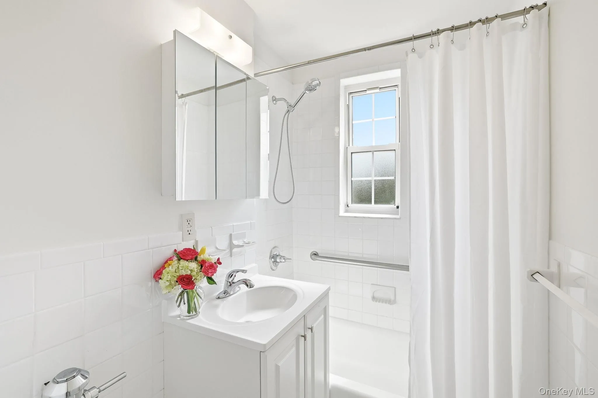 Clean, classic white-on-white bathroom with new vanity/sink/faucet and with newly caulked wall and floor ceramic tile Clean, classic white-on-white bathroom with new vanity/sink/faucet and with newly caulked wall and floor ceramic tile