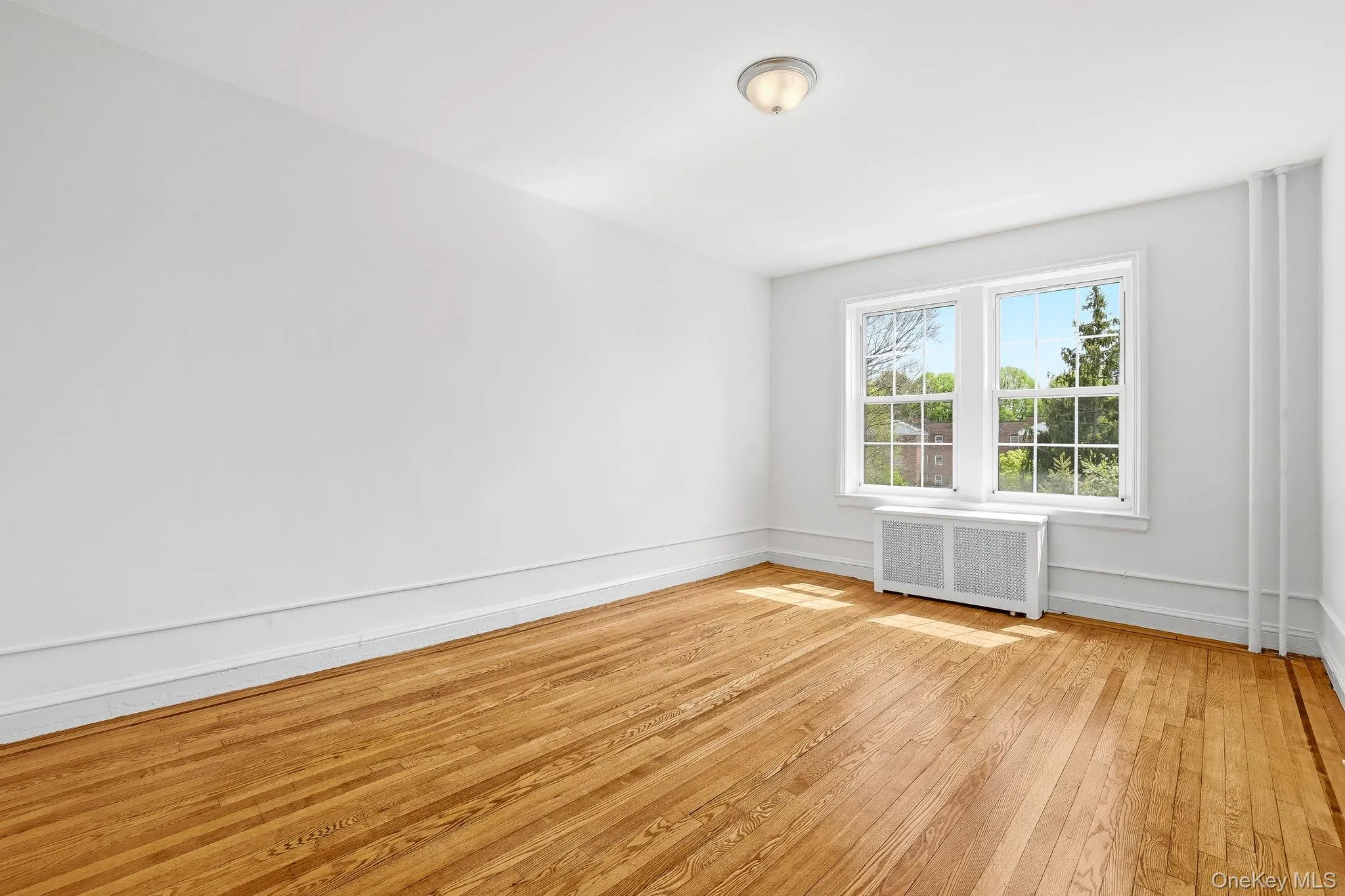 The primary bedroom has newly-polished wood floors and facing south, overlooks the front courtyard The primary bedroom has newly-polished wood floors and facing south, overlooks the front courtyard
