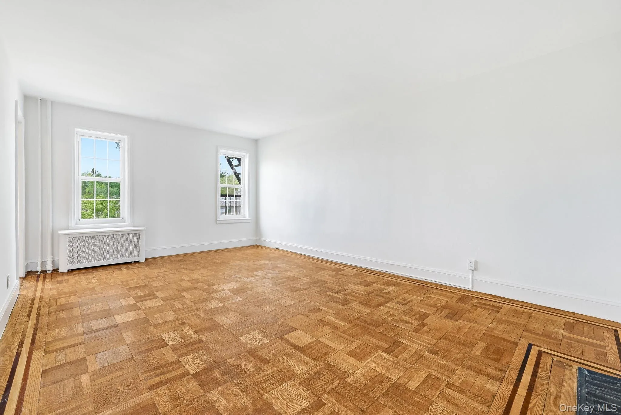 There are beautiful wood parquet floors in the living room, with windows facing north and with views of the greenery around this complex There are beautiful wood parquet floors in the living room, with windows facing north and with views of the greenery around this complex