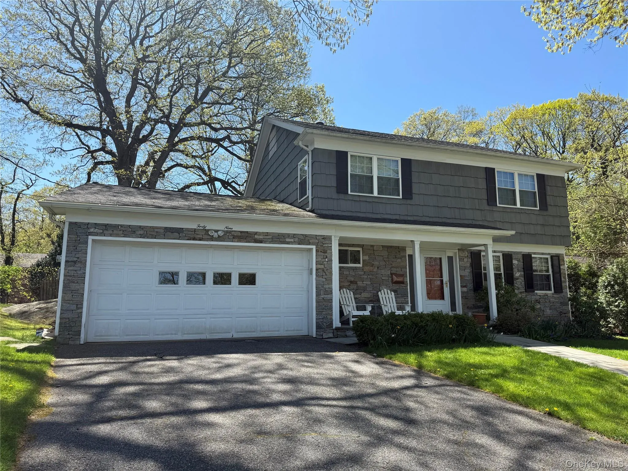 View of front of property featuring covered porch, aphalt driveway, an attached garage, and stone siding View of front of property featuring covered porch, aphalt driveway, an attached garage, and stone siding