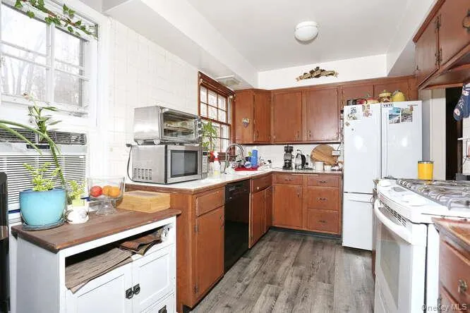 Kitchen featuring stainless steel microwave, light wood-type flooring, white gas range, dishwasher, and a sink Kitchen featuring stainless steel microwave, light wood-type flooring, white gas range, dishwasher, and a sink