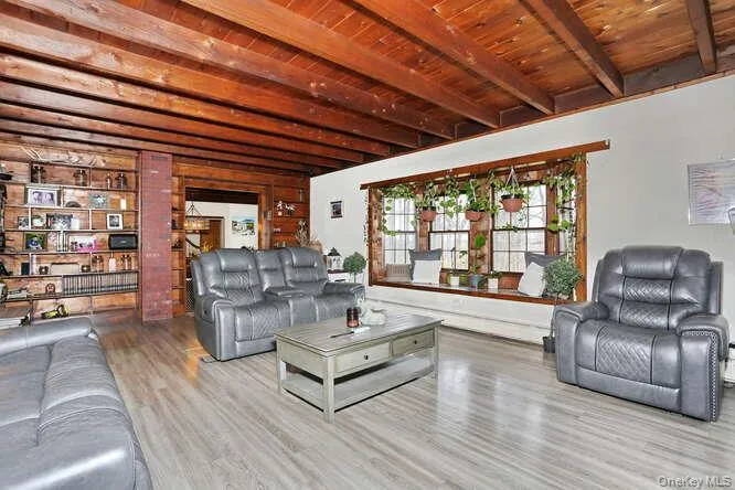 Living room with beamed ceiling, wooden ceiling, and wood finished floors Living room with beamed ceiling, wooden ceiling, and wood finished floors