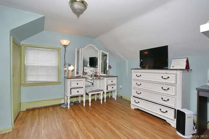 Bedroom with light wood-style flooring, a baseboard heating unit, and lofted ceiling Bedroom with light wood-style flooring, a baseboard heating unit, and lofted ceiling