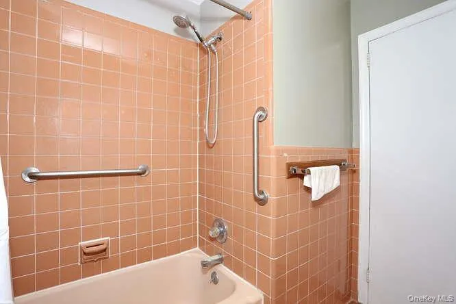 Bathroom featuring wainscoting, shower / washtub combination, and tile walls Bathroom featuring wainscoting, shower / washtub combination, and tile walls