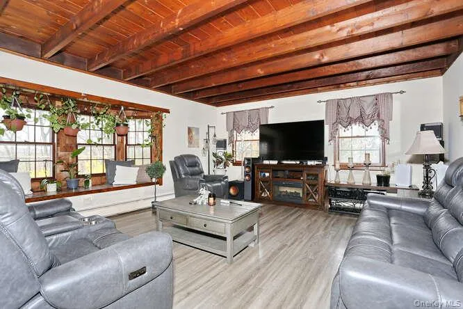 Living area featuring beamed ceiling, a wealth of natural light, and wood ceiling Living area featuring beamed ceiling, a wealth of natural light, and wood ceiling