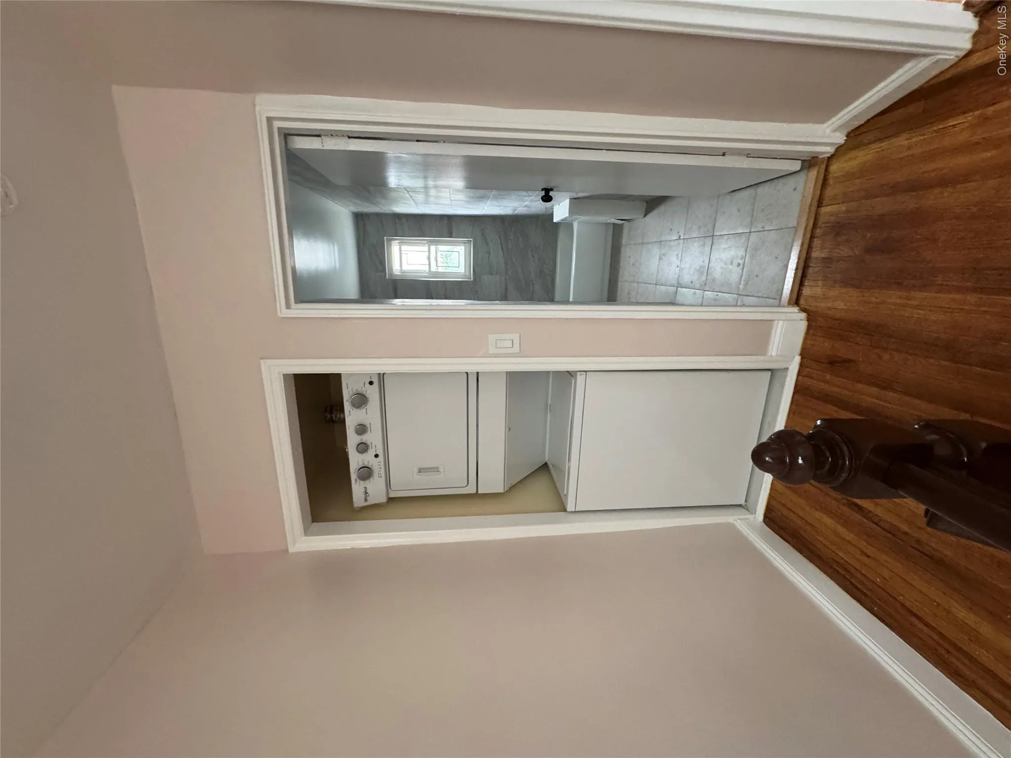 Laundry area featuring hardwood / wood-style flooring and stacked washer and clothes dryer Laundry area featuring hardwood / wood-style flooring and stacked washer and clothes dryer