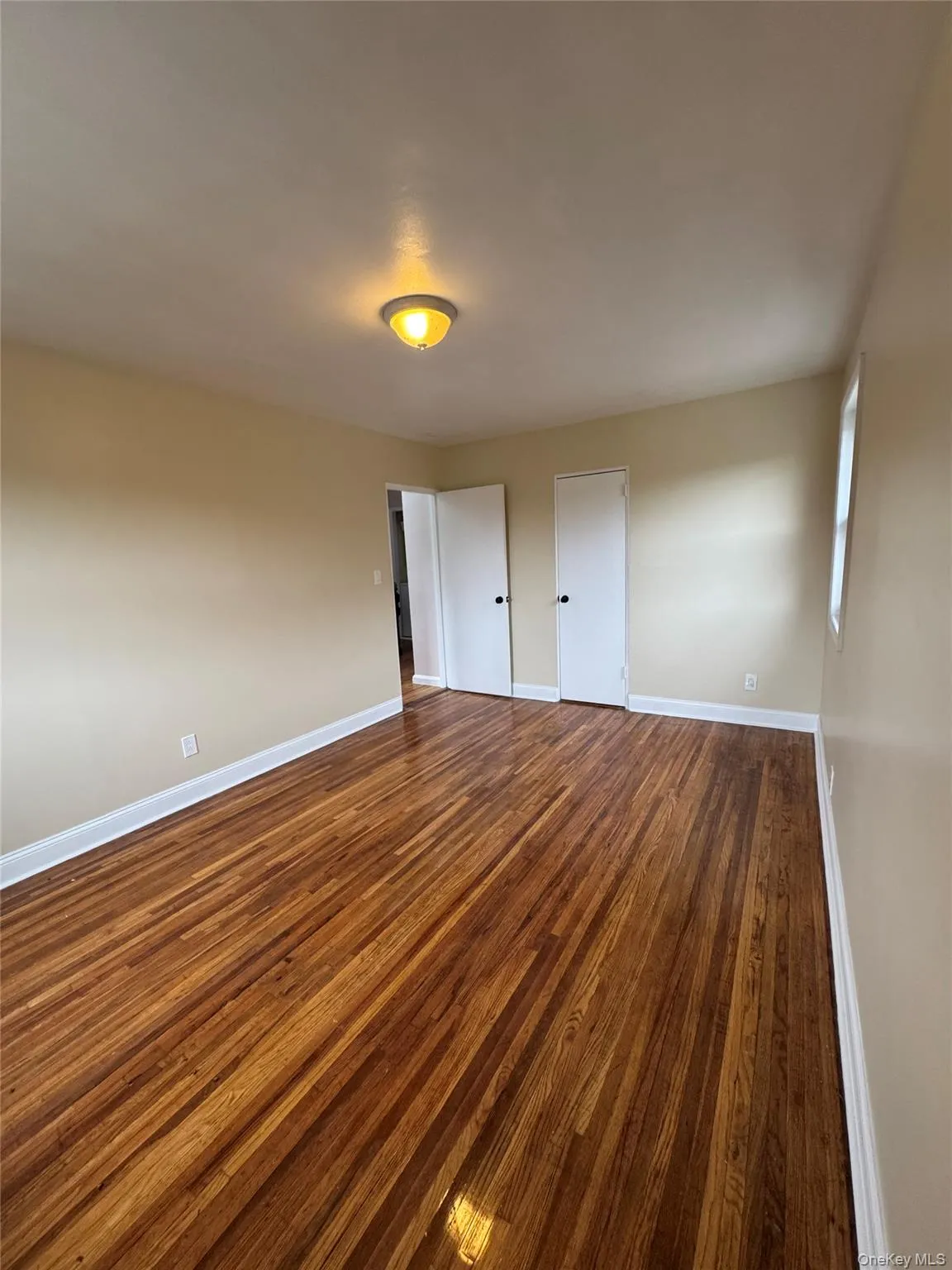 Spare room with dark wood-style floors and baseboards Spare room with dark wood-style floors and baseboards