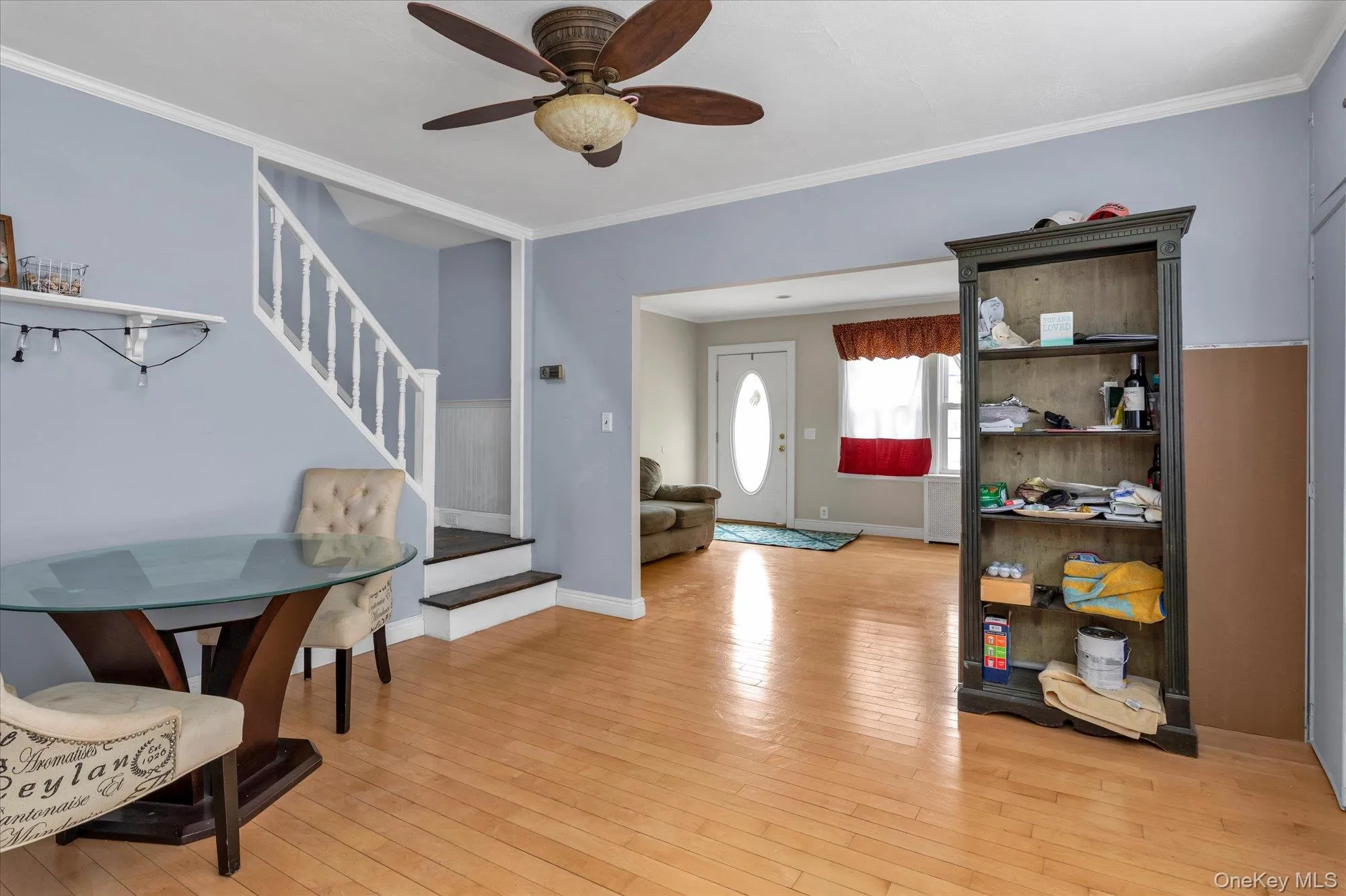 Bright living area featuring light wood-finish flooring, a ceiling fan, and white trim Bright living area featuring light wood-finish flooring, a ceiling fan, and white trim