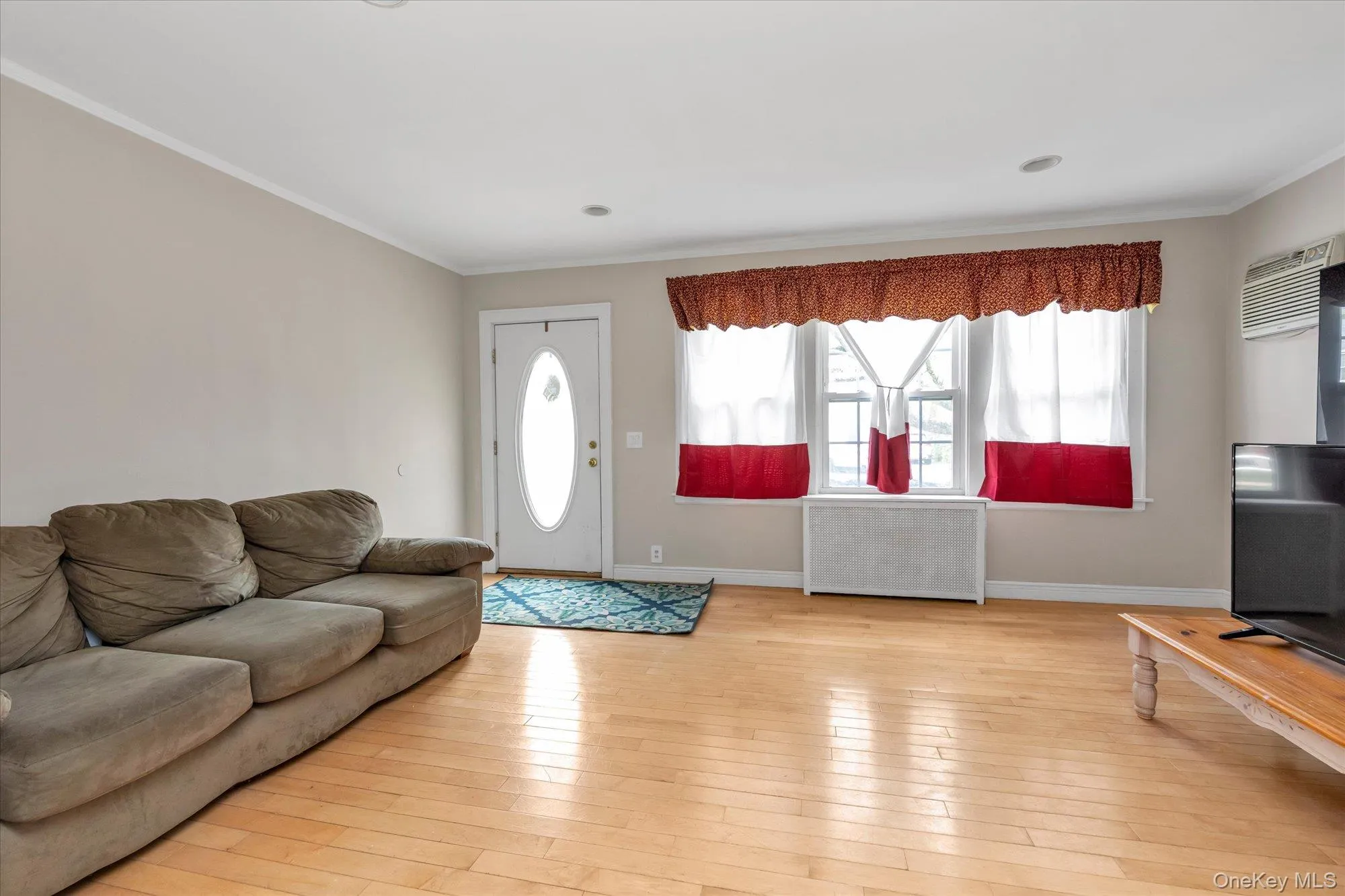 Entry area with wood-finish flooring, light neutral wall paint, and a bright white oval-lite entry door Entry area with wood-finish flooring, light neutral wall paint, and a bright white oval-lite entry door