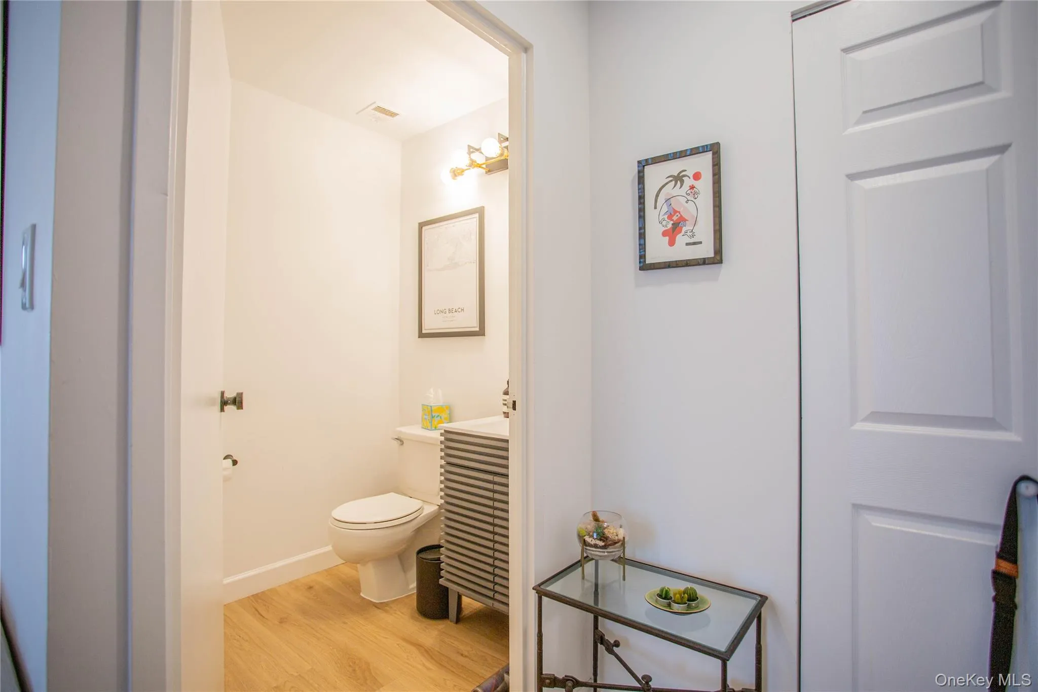 Bathroom with toilet, baseboards, vanity, and wood finished floors Bathroom with toilet, baseboards, vanity, and wood finished floors