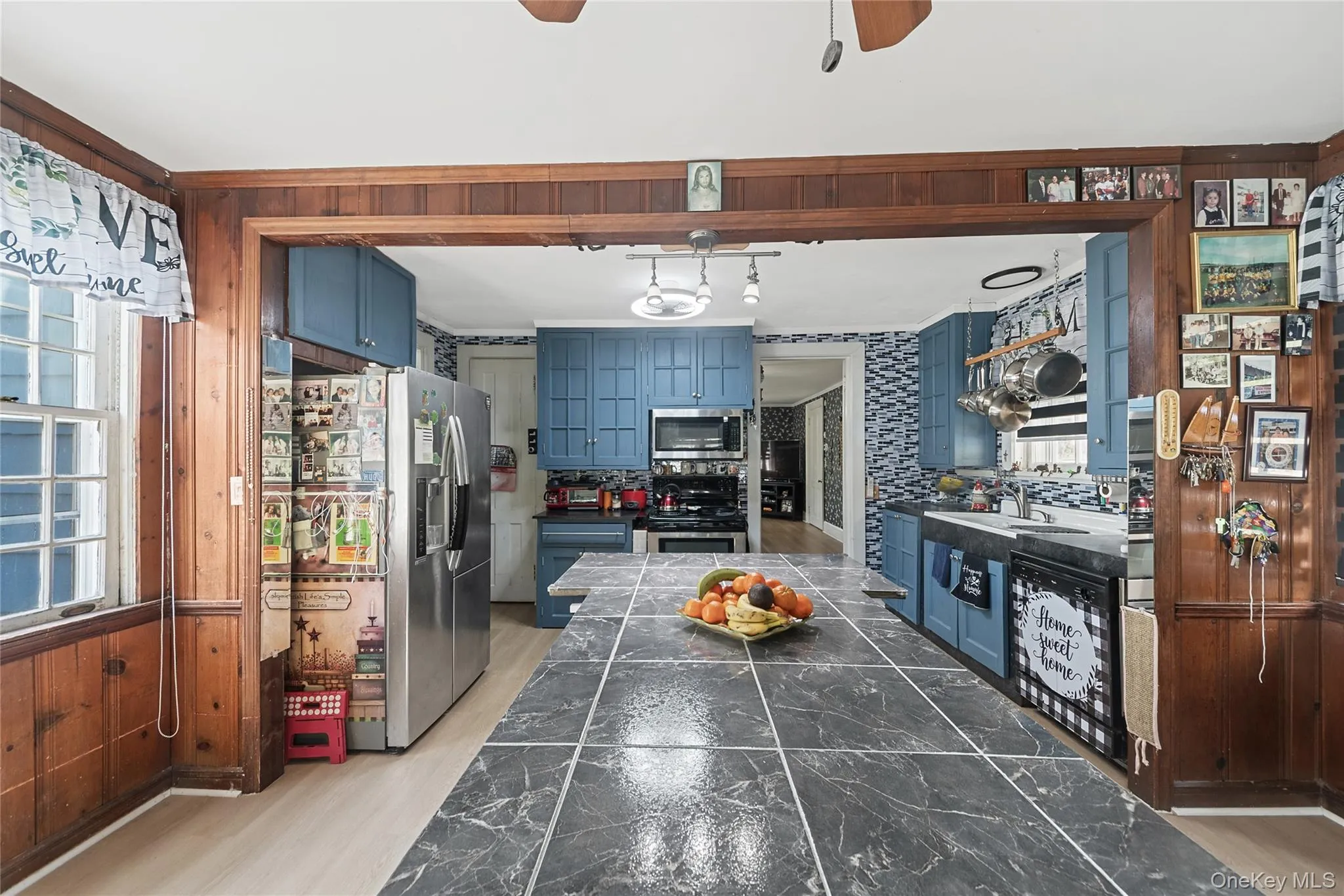 Kitchen featuring blue cabinetry, a tiled backsplash, and a large island with a tiled countertop Kitchen featuring blue cabinetry, a tiled backsplash, and a large island with a tiled countertop