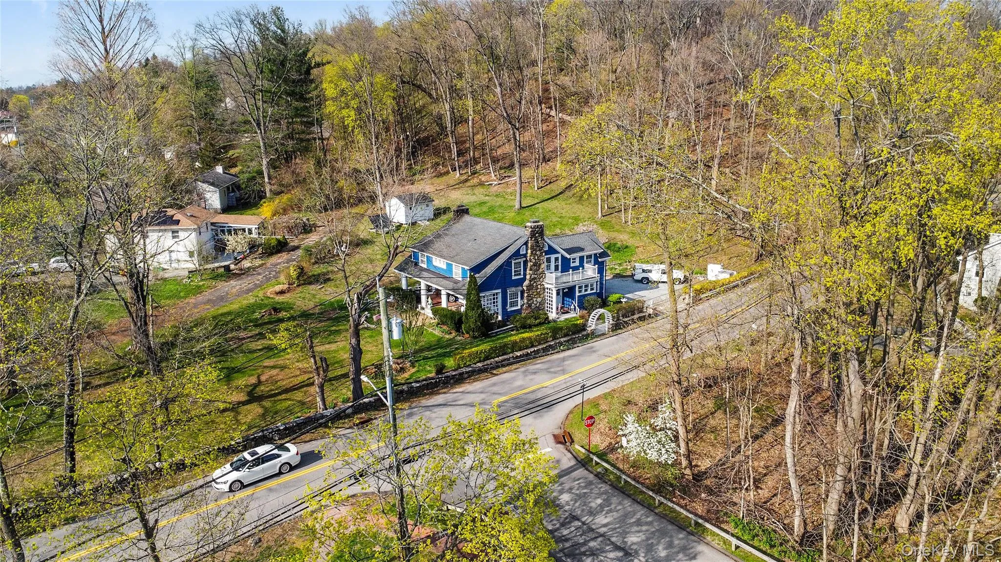 Blue-sided residence with a prominent stone chimney, set on a sloped lot Blue-sided residence with a prominent stone chimney, set on a sloped lot