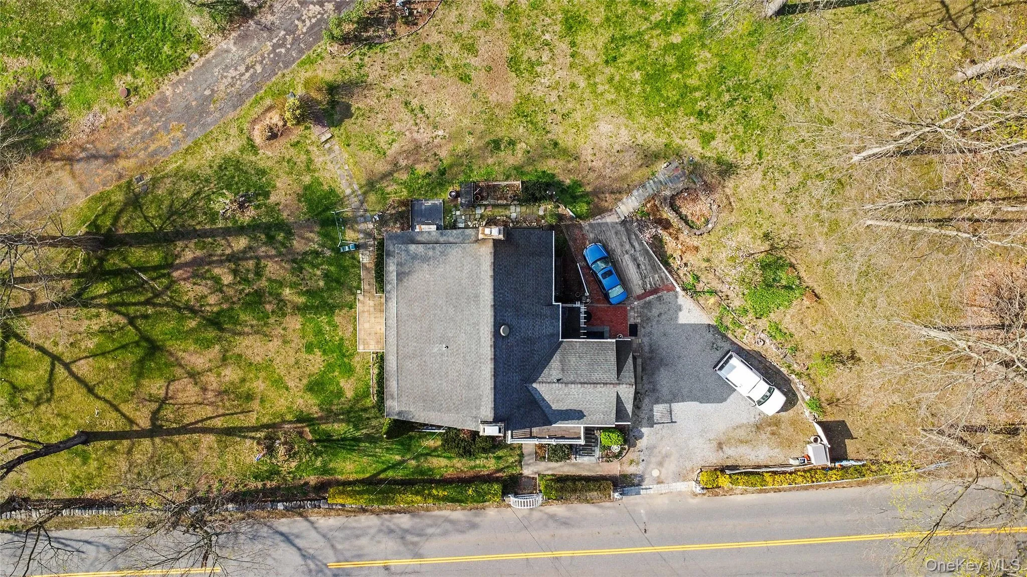 Property with a shingle roof, a paved driveway, and a front yard featuring mature trees Property with a shingle roof, a paved driveway, and a front yard featuring mature trees