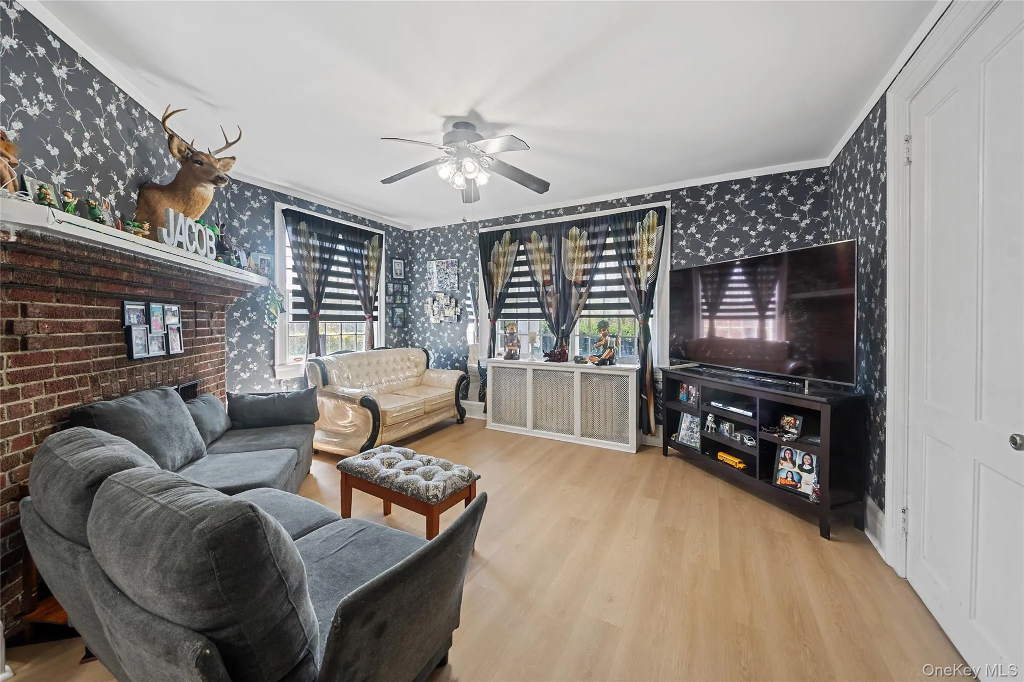 Living space featuring wood-finish flooring, a ceiling fan with integrated lighting, and white crown molding Living space featuring wood-finish flooring, a ceiling fan with integrated lighting, and white crown molding