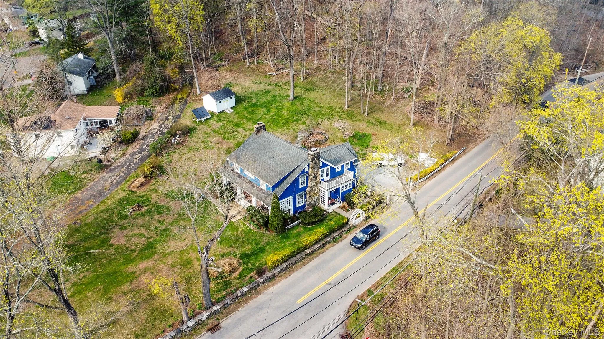Two-story residence featuring blue siding, white trim, and a prominent stone chimney Two-story residence featuring blue siding, white trim, and a prominent stone chimney