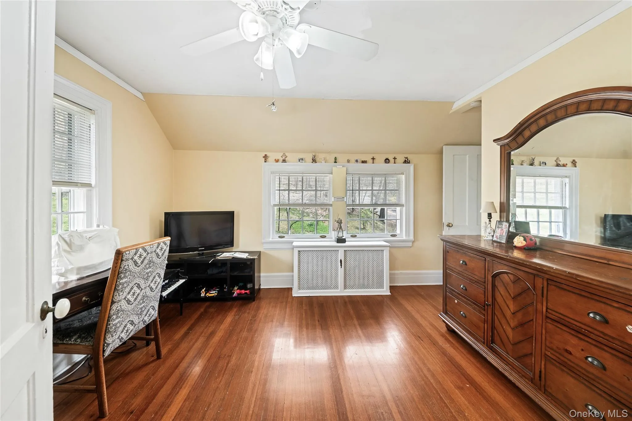 Hardwood flooring throughout this room featuring a ceiling fan, two double-hung windows, and a white paneled door Hardwood flooring throughout this room featuring a ceiling fan, two double-hung windows, and a white paneled door