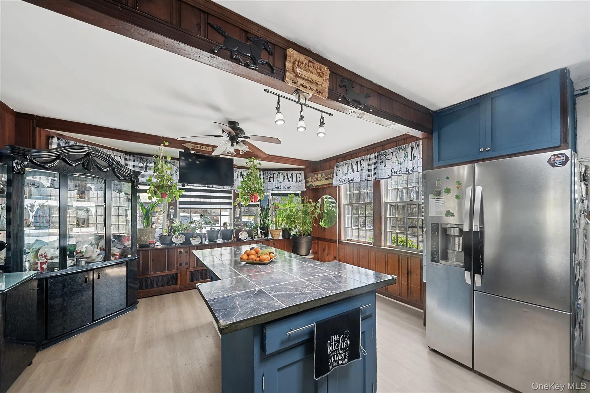 Kitchen featuring wood-paneled walls, light wood-finish flooring, and a ceiling fan Kitchen featuring wood-paneled walls, light wood-finish flooring, and a ceiling fan