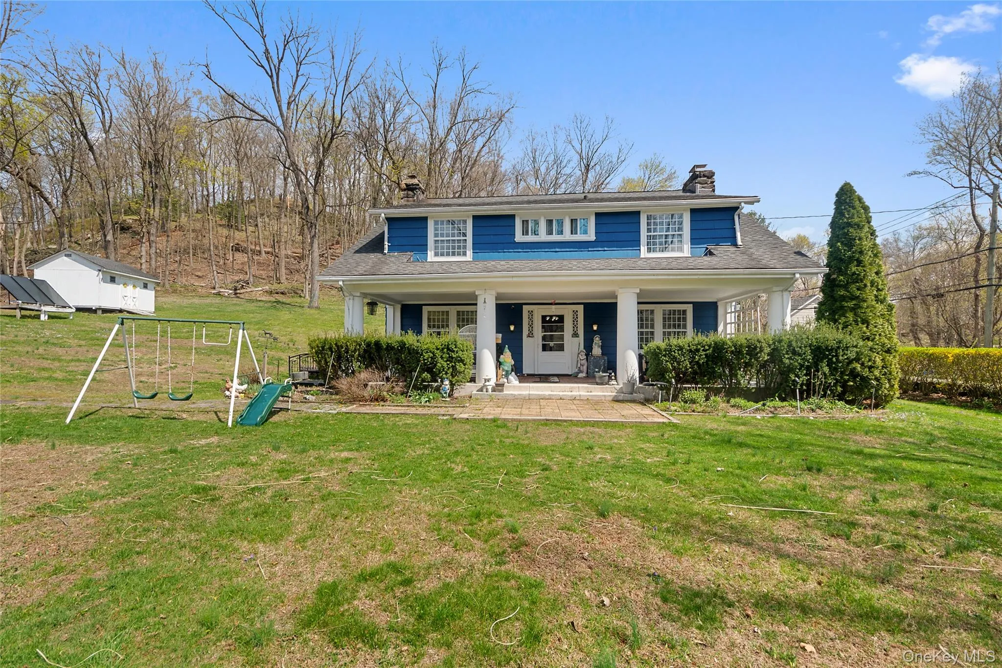 Blue siding exterior with a covered front porch, white columns, and multiple windows Blue siding exterior with a covered front porch, white columns, and multiple windows