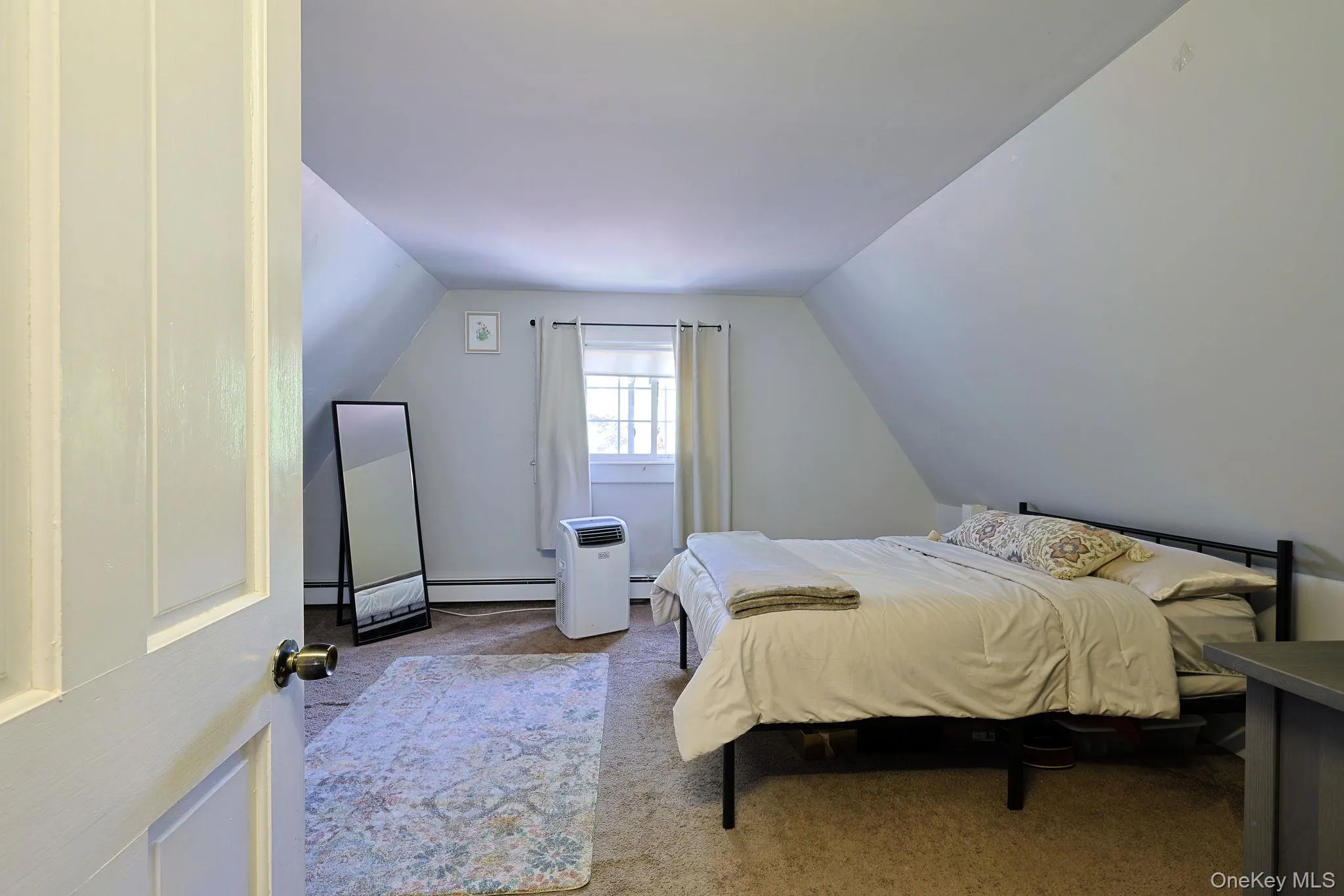 Carpeted room with sloped ceilings and a single window Carpeted room with sloped ceilings and a single window