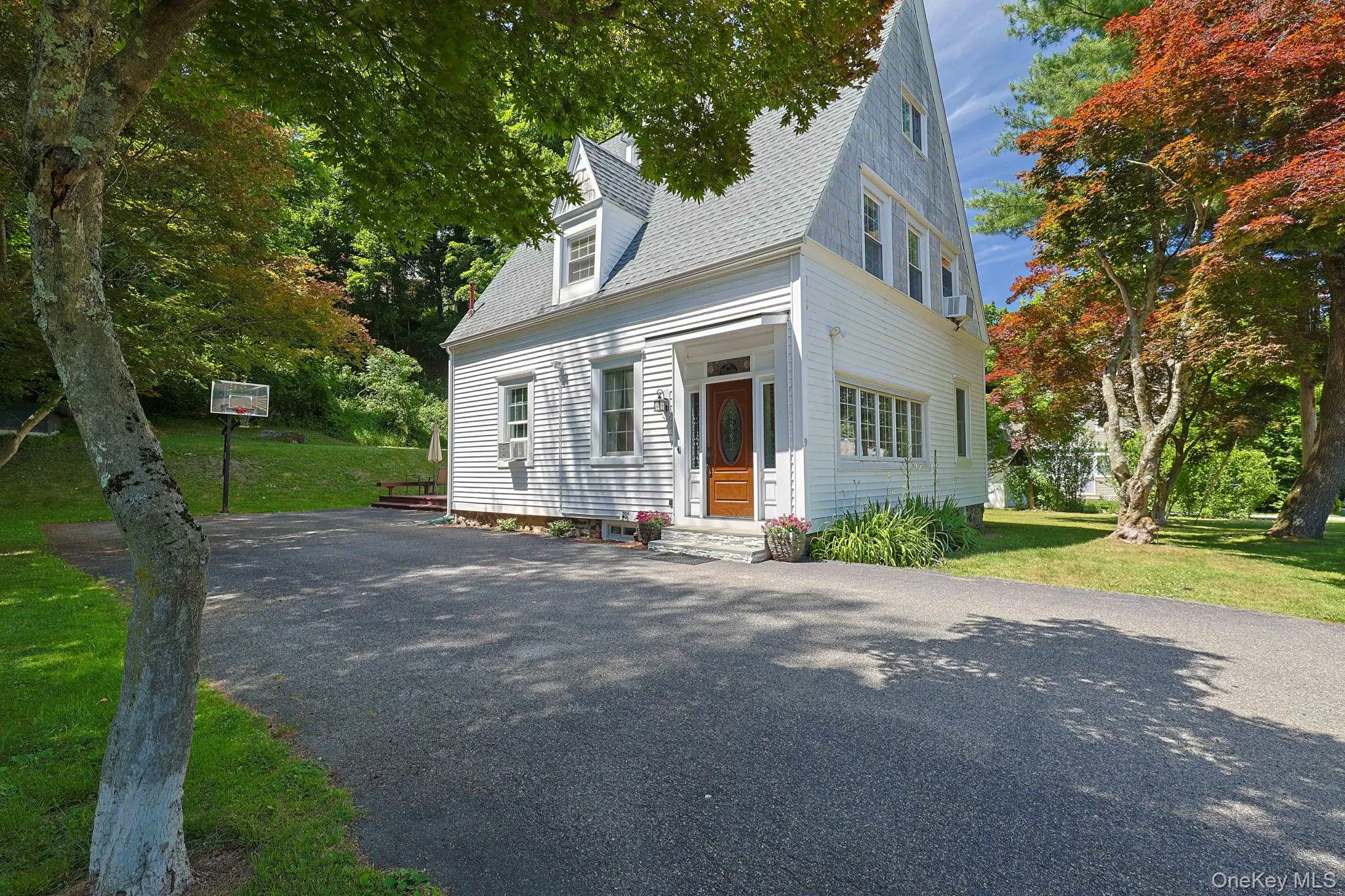 White clapboard exterior with a steep-pitched roofline and dormer windows/expansive driveway White clapboard exterior with a steep-pitched roofline and dormer windows/expansive driveway