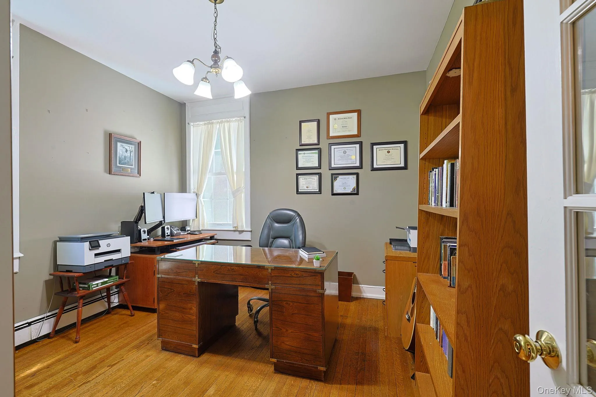 Office/Den/ possible as additional bedroom featuring hardwood flooring, a window with natural light, and a built-in wooden bookcase Office/Den/ possible as additional bedroom featuring hardwood flooring, a window with natural light, and a built-in wooden bookcase