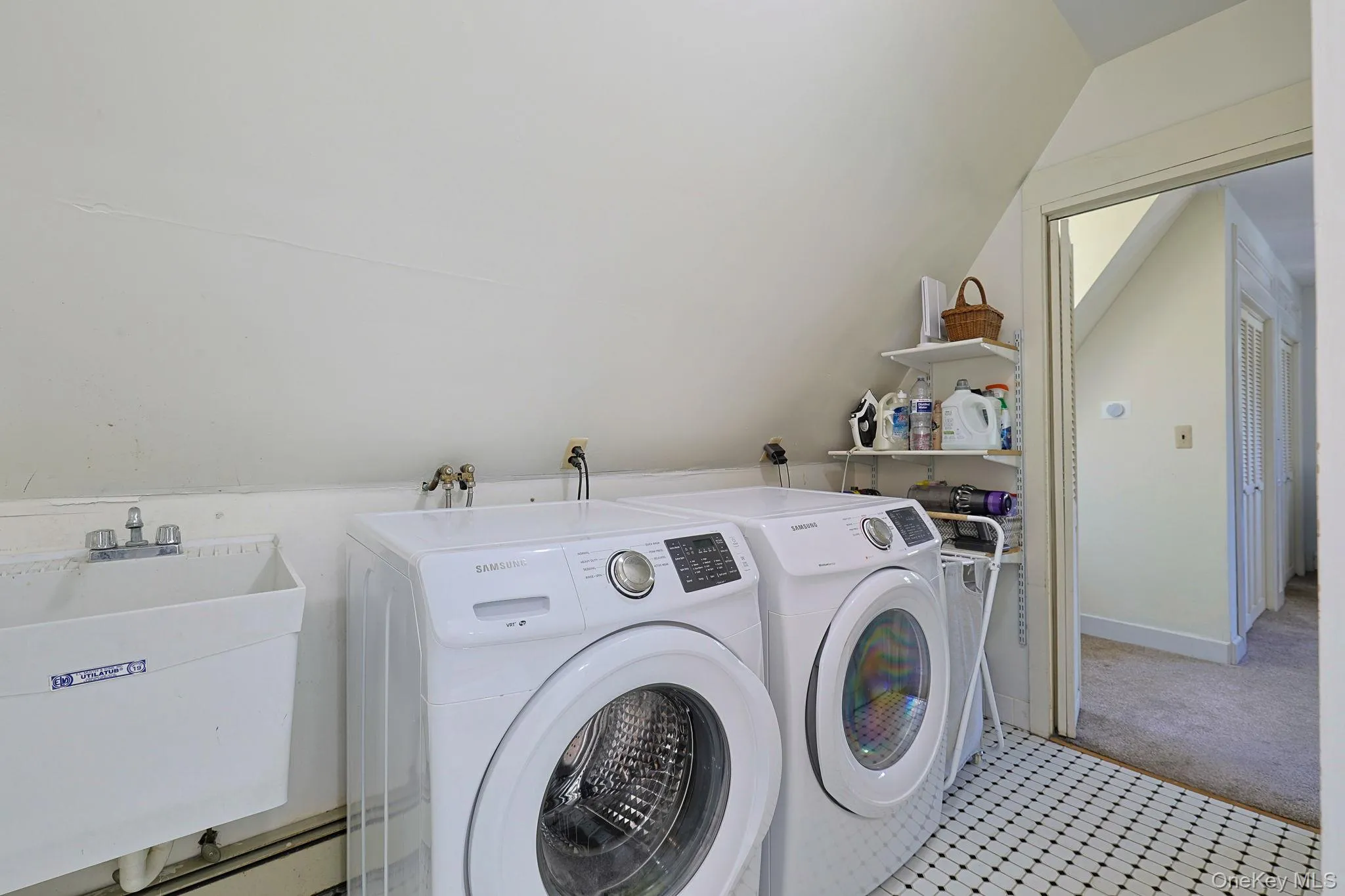 Dedicated laundry area on second floor featuring a Utility sink with a two-handle faucet, black and white mosaic tile flooring, and built-in wall shelving Dedicated laundry area on second floor featuring a Utility sink with a two-handle faucet, black and white mosaic tile flooring, and built-in wall shelving