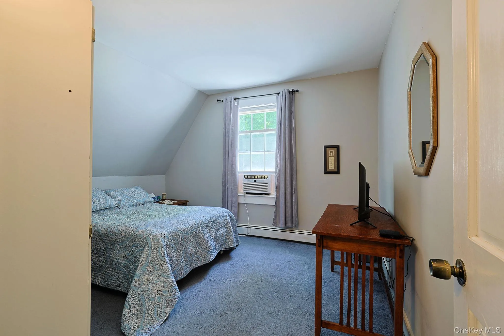 Bedroom with sloped ceilings, a double window, and soft blue carpeting Bedroom with sloped ceilings, a double window, and soft blue carpeting