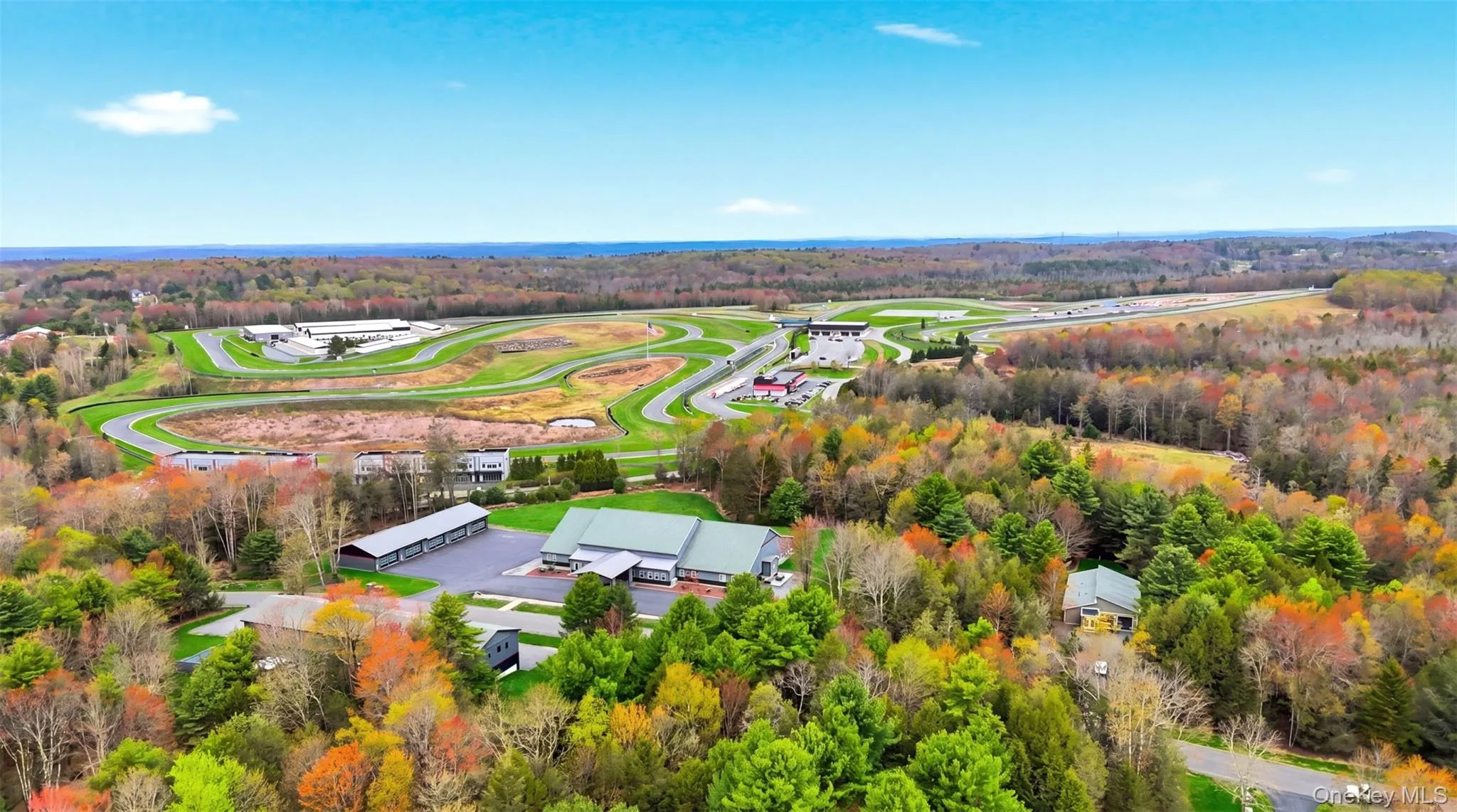 Expansive property featuring a circuit track, multiple buildings with green roofs, and a large paved parking area Expansive property featuring a circuit track, multiple buildings with green roofs, and a large paved parking area