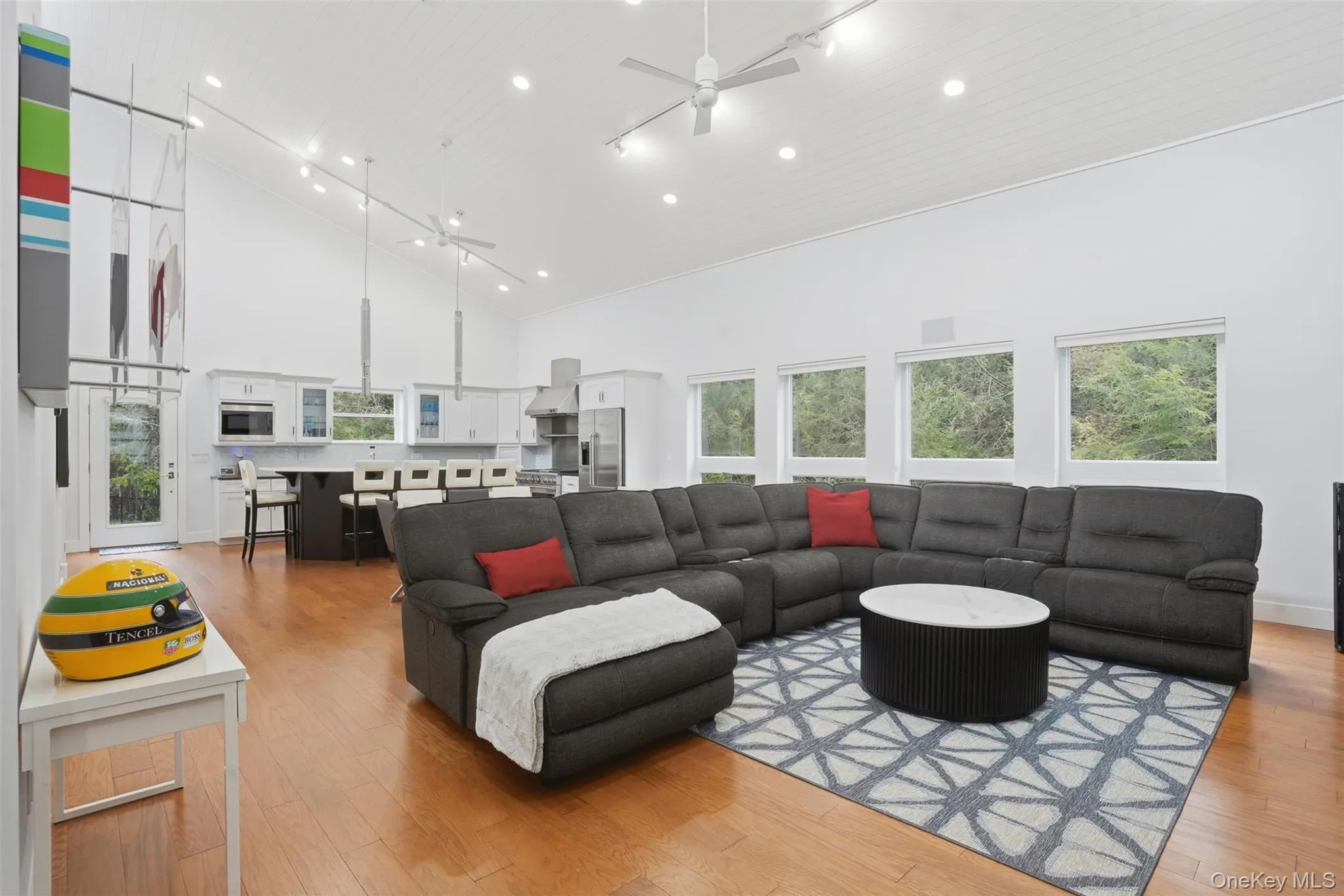 Expansive open-concept living area featuring high vaulted ceilings, recessed lighting, and wood-finish flooring Expansive open-concept living area featuring high vaulted ceilings, recessed lighting, and wood-finish flooring
