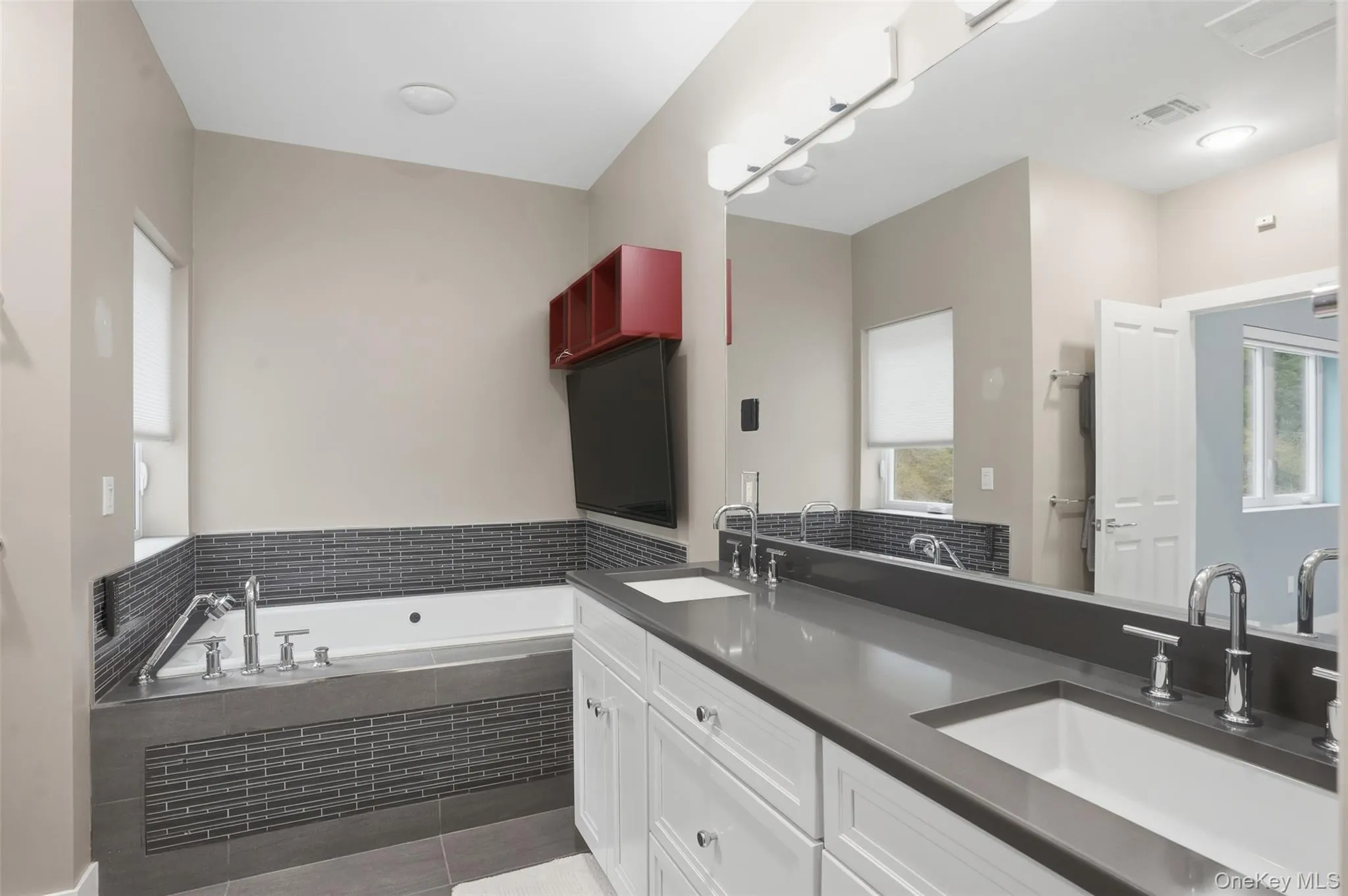 Dual vanity featuring white cabinetry, chrome fixtures, and a dark stone countertop Dual vanity featuring white cabinetry, chrome fixtures, and a dark stone countertop