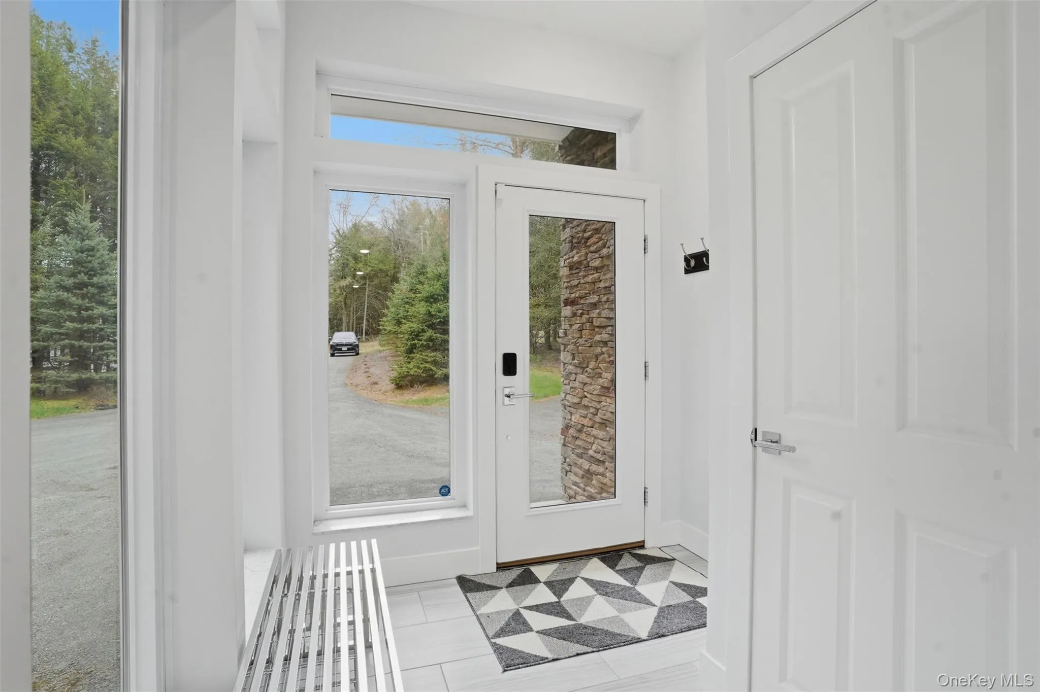 Bright entryway featuring a full-light glass entry door, side windows, transom window, and tiled flooring Bright entryway featuring a full-light glass entry door, side windows, transom window, and tiled flooring