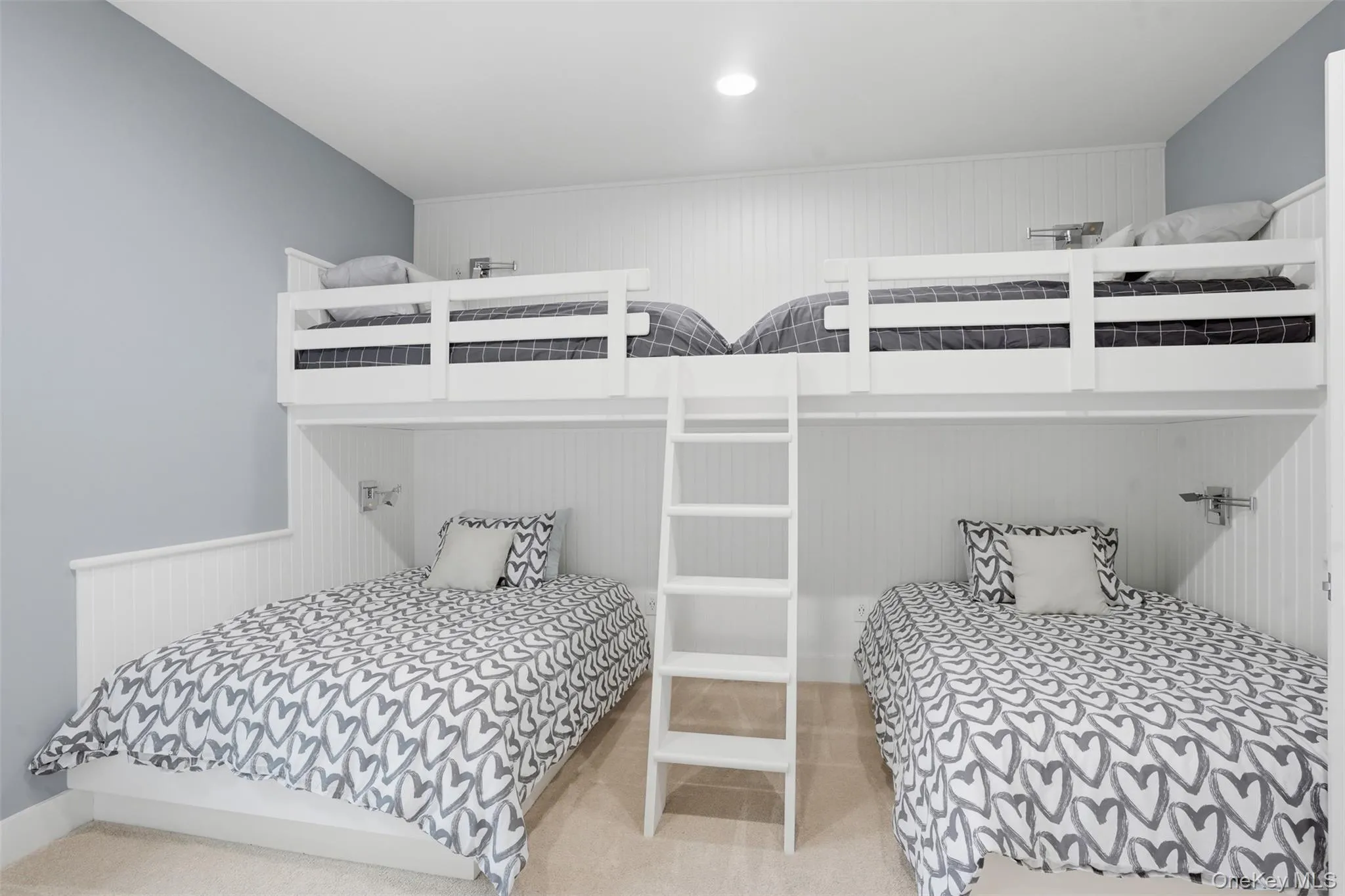 Built-in bunk beds featuring white wood construction and a white ladder Built-in bunk beds featuring white wood construction and a white ladder