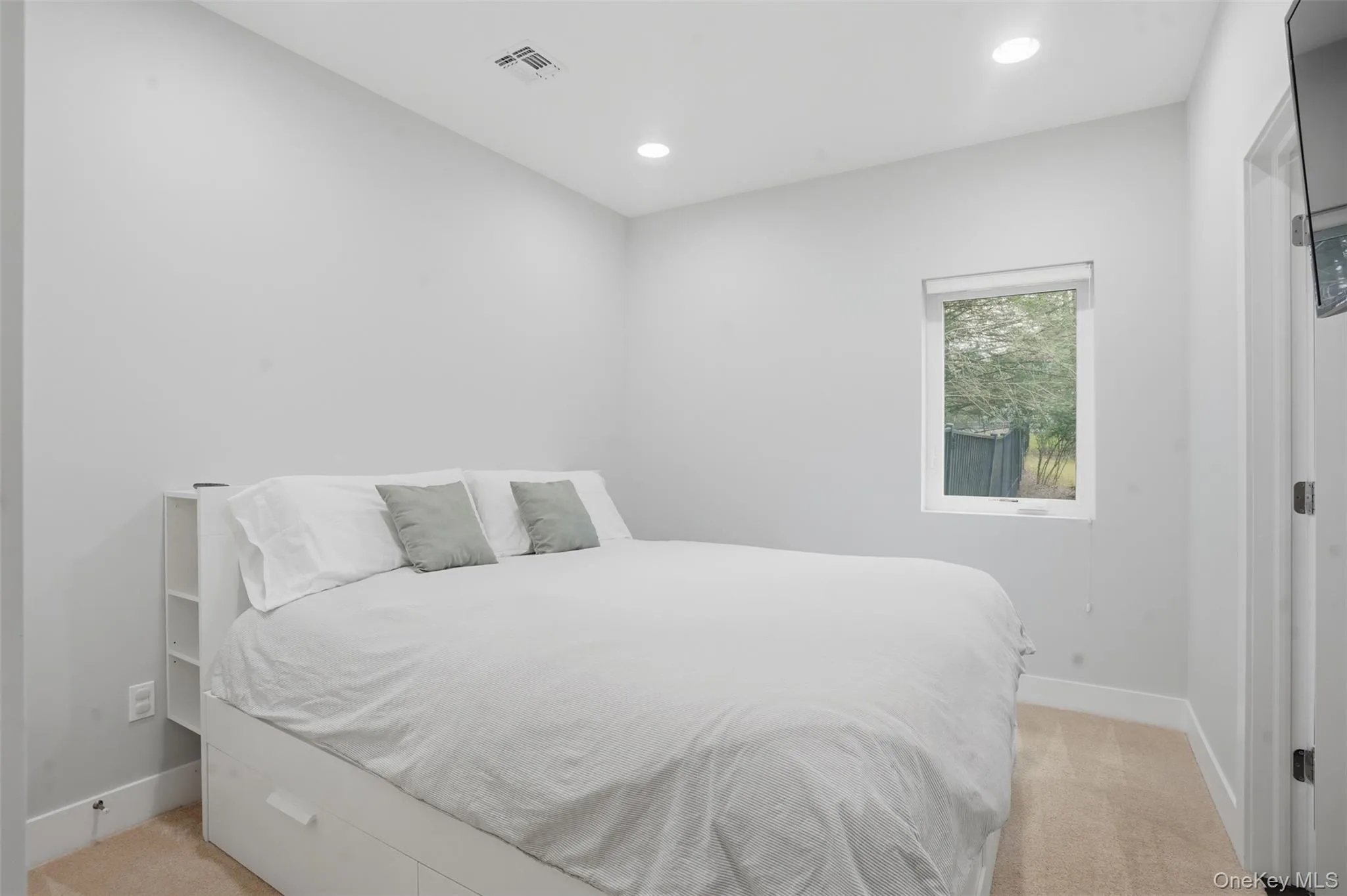 Bright room featuring a single window, recessed lighting, and light-colored carpeting Bright room featuring a single window, recessed lighting, and light-colored carpeting
