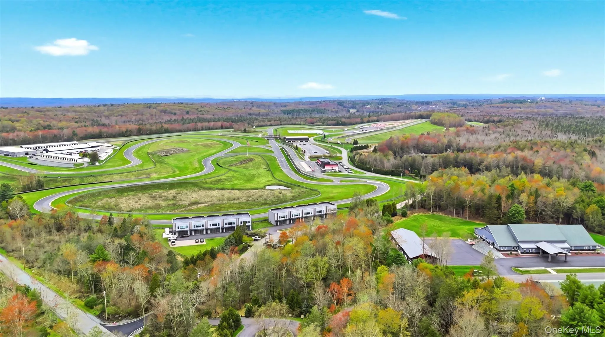 Aerial perspective showcasing expansive grounds with a paved track system, multiple buildings, and mature perimeter trees Aerial perspective showcasing expansive grounds with a paved track system, multiple buildings, and mature perimeter trees